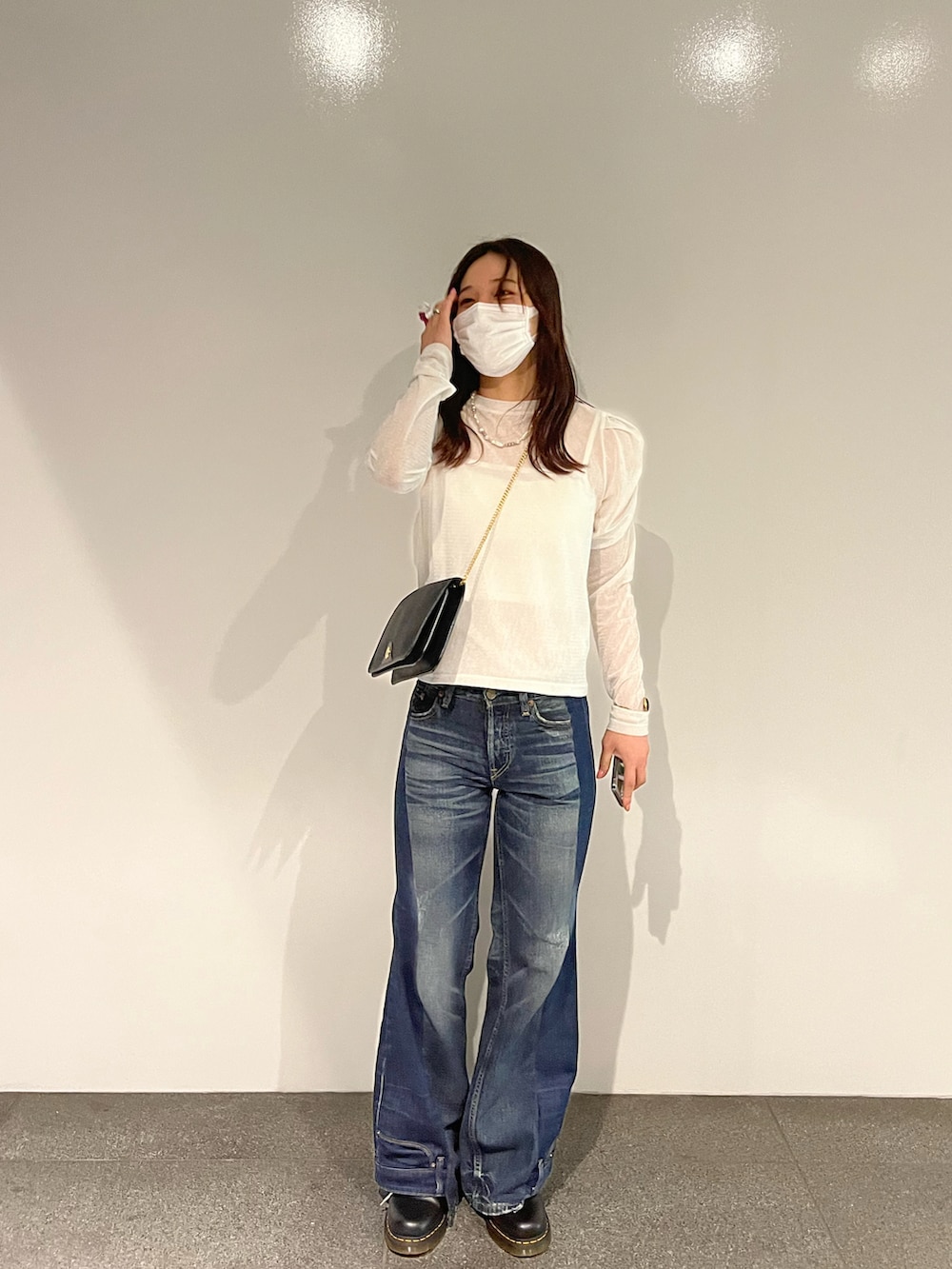 ブルー系のデニムパンツ、ホワイト系のTシャツ/カットソー、ブラック系のバッグを着用したレディースの秋コーディネートの2枚目の写真