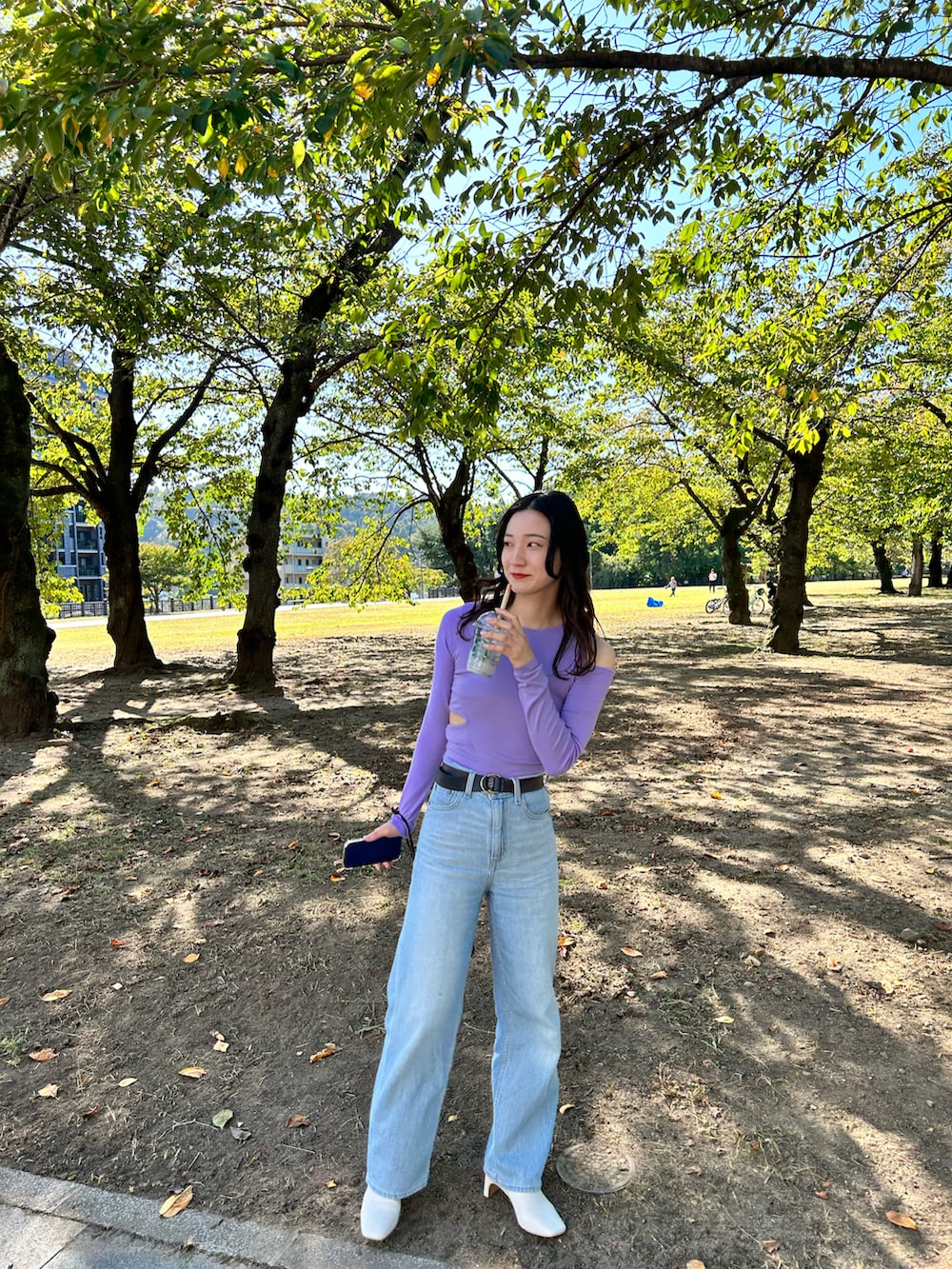 パープル系のTシャツ/カットソー、ブルー系のデニムパンツ、ブラック系のバッグを着用したレディースの秋コーディネートの2枚目の写真