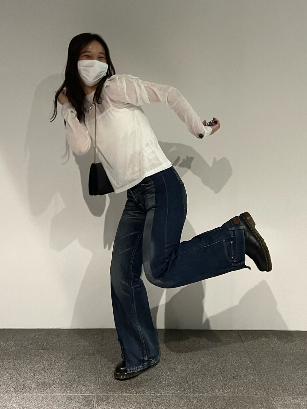 ブルー系のデニムパンツ、ホワイト系のTシャツ/カットソー、ブラック系のバッグを着用したレディースの秋コーディネートの4枚目の写真