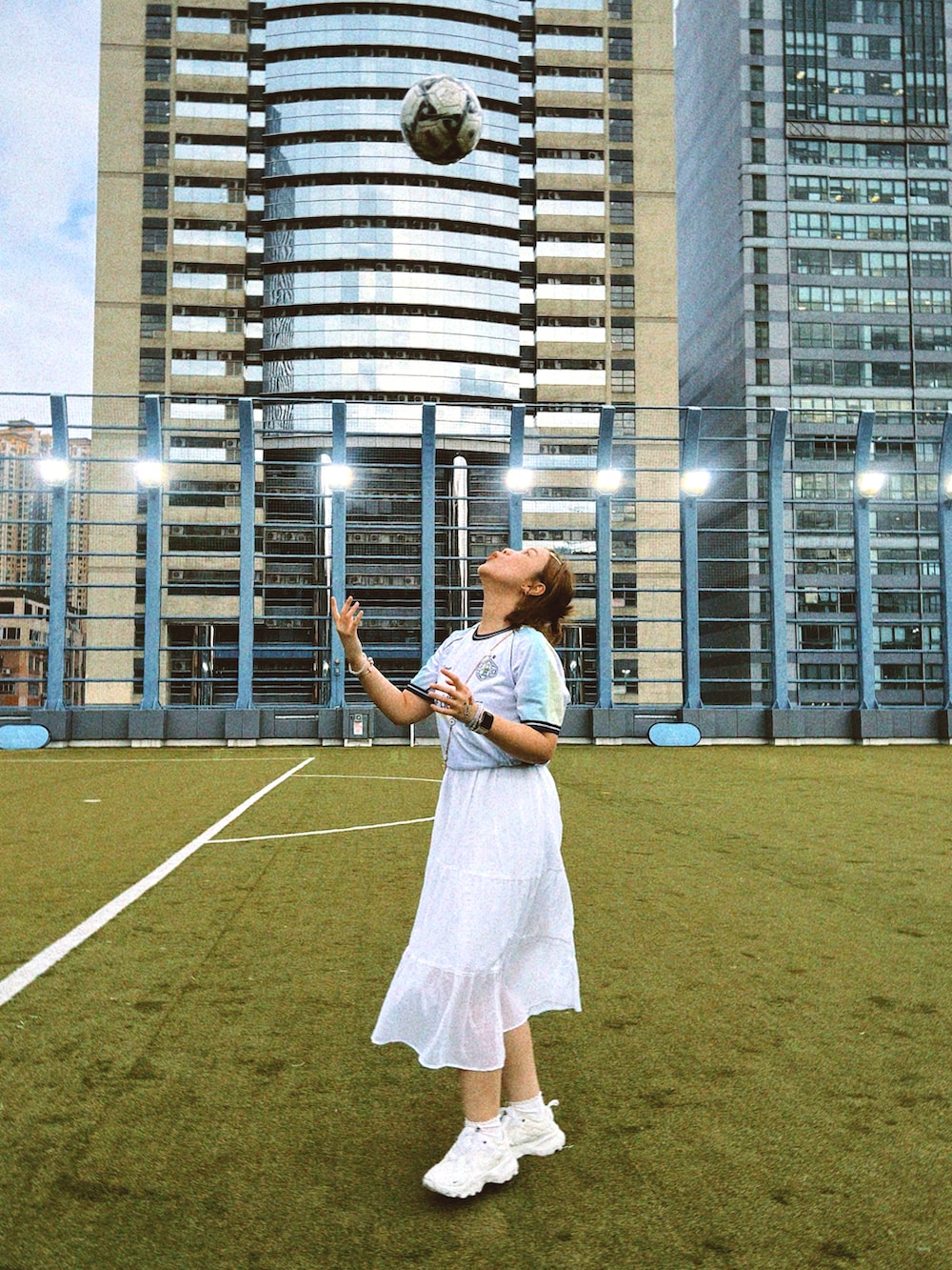 ホワイト系のジャンパースカート、ホワイト系のスニーカーを着用したレディースの春コーディネートの2枚目の写真