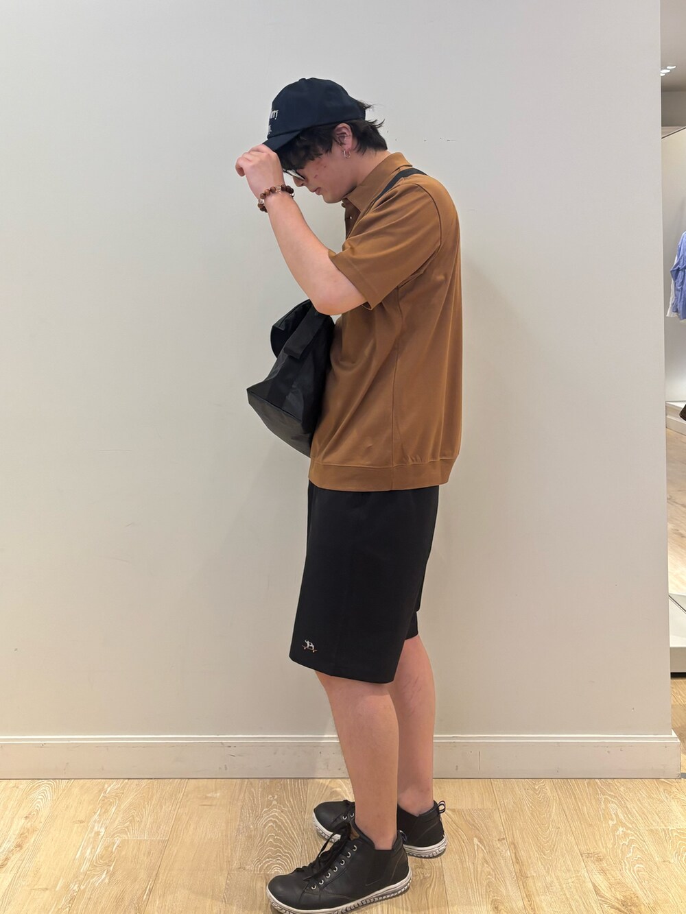 ブラック系のショルダーバッグ、イエロー系のポロシャツ、ブルー系のキャップを着用したメンズの夏コーディネートの3枚目の写真