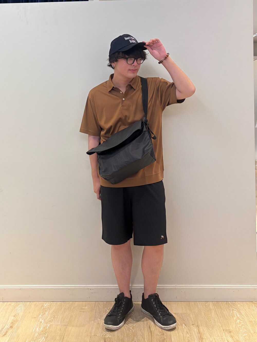 ブラック系のショルダーバッグ、イエロー系のポロシャツ、ブルー系のキャップを着用したメンズの夏コーディネートの2枚目の写真