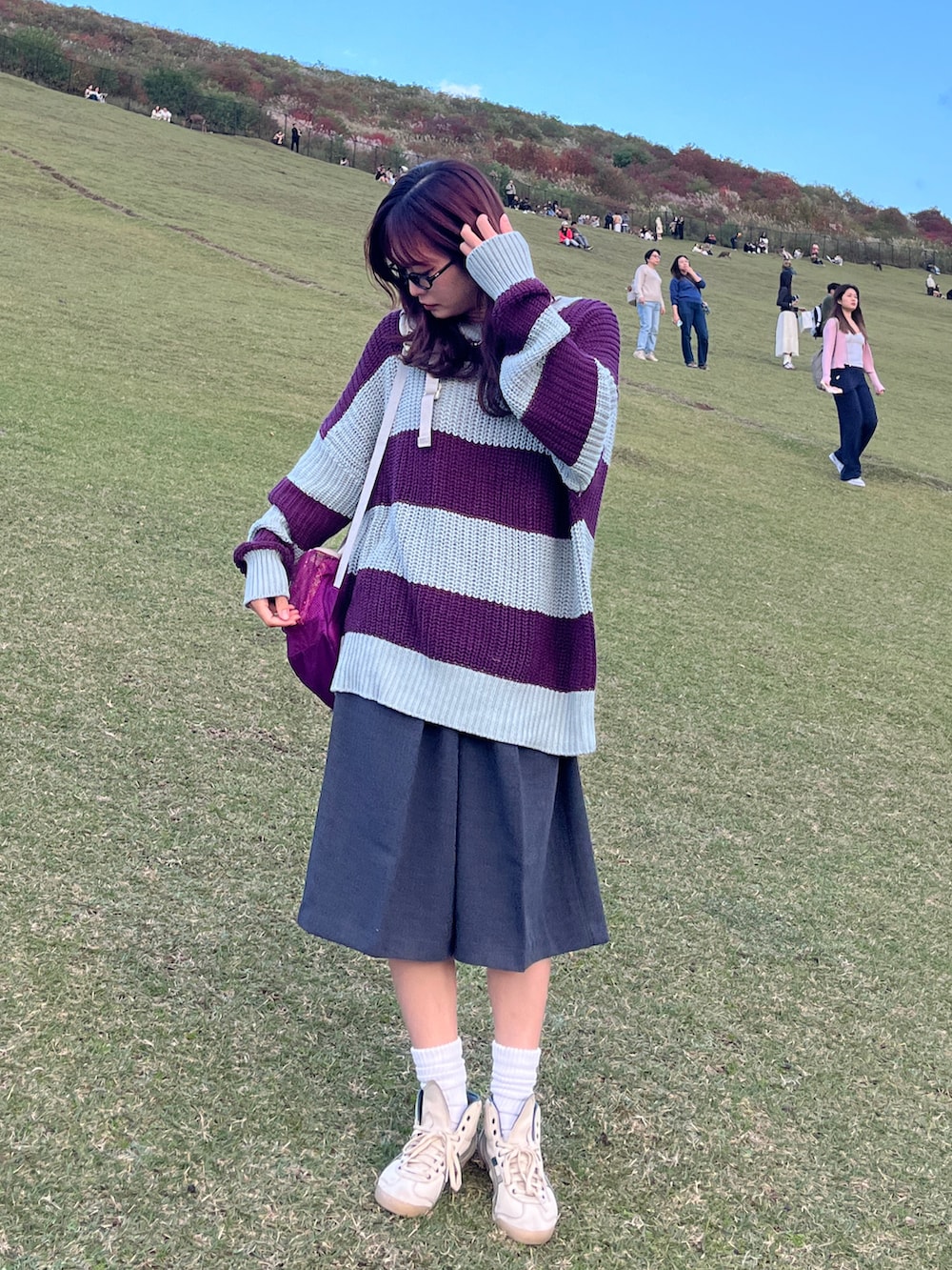 グレー系のその他パンツ、パープル系のニット/セーター、ベージュ系のスニーカーを着用したレディースの秋コーディネートの2枚目の写真