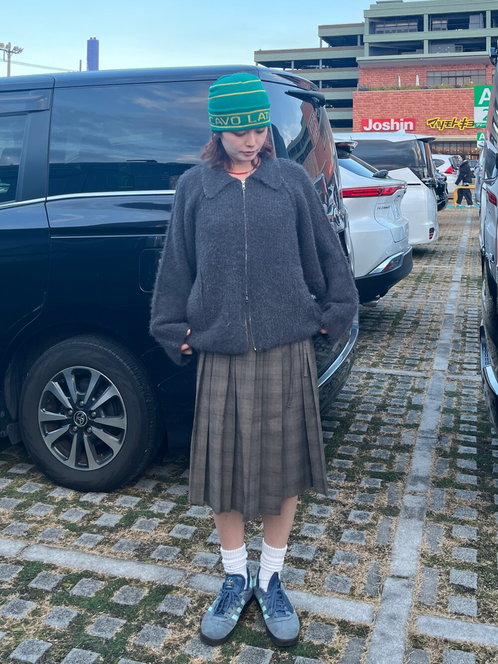 グレー系のニット/セーター、ブラウン系のスカート、ブルー系のスニーカーを着用したレディースの冬コーディネートの2枚目の写真