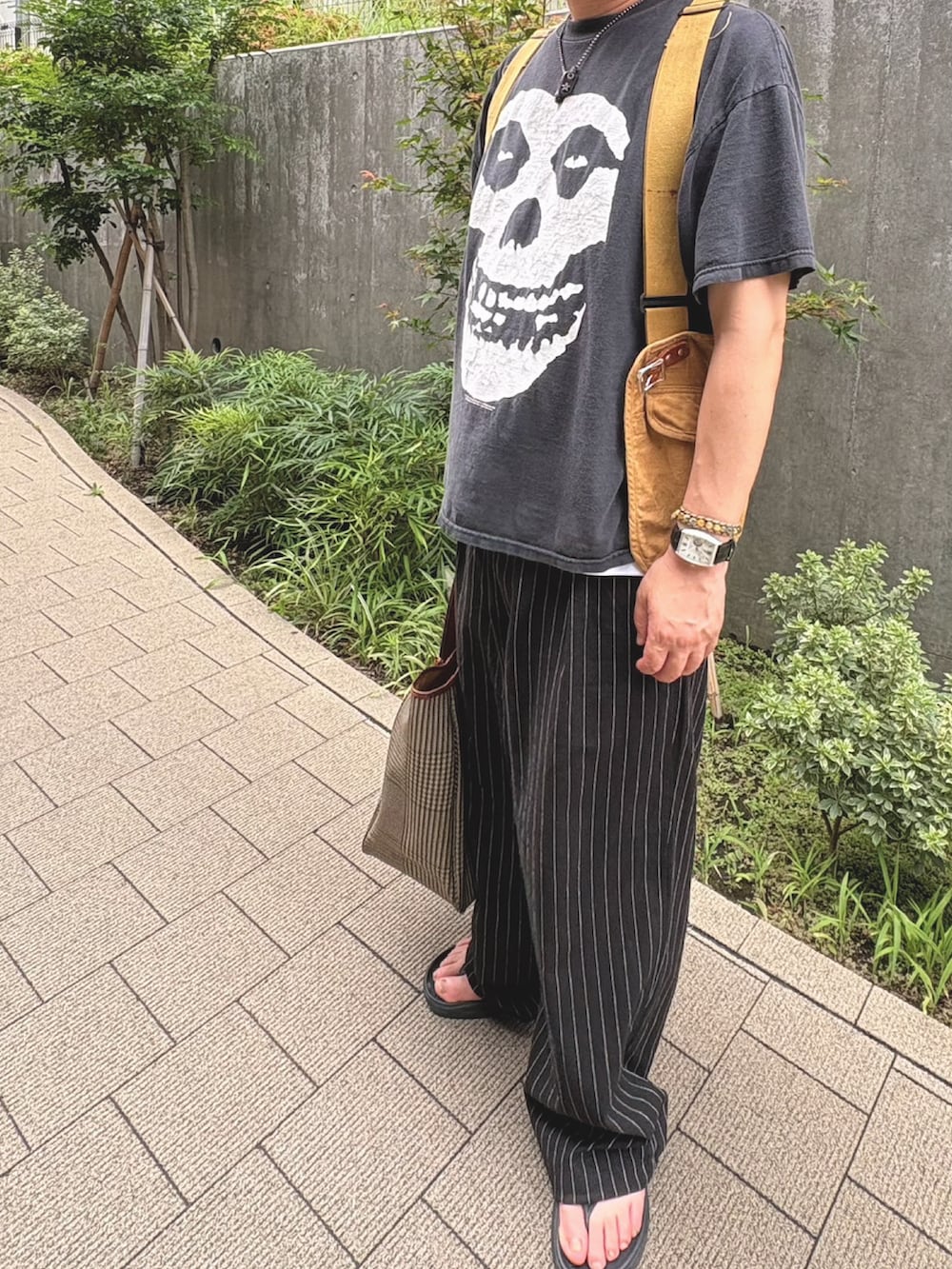 ブラック系のパンツ、イエロー系のベストを着用したメンズの夏コーディネートの2枚目の写真