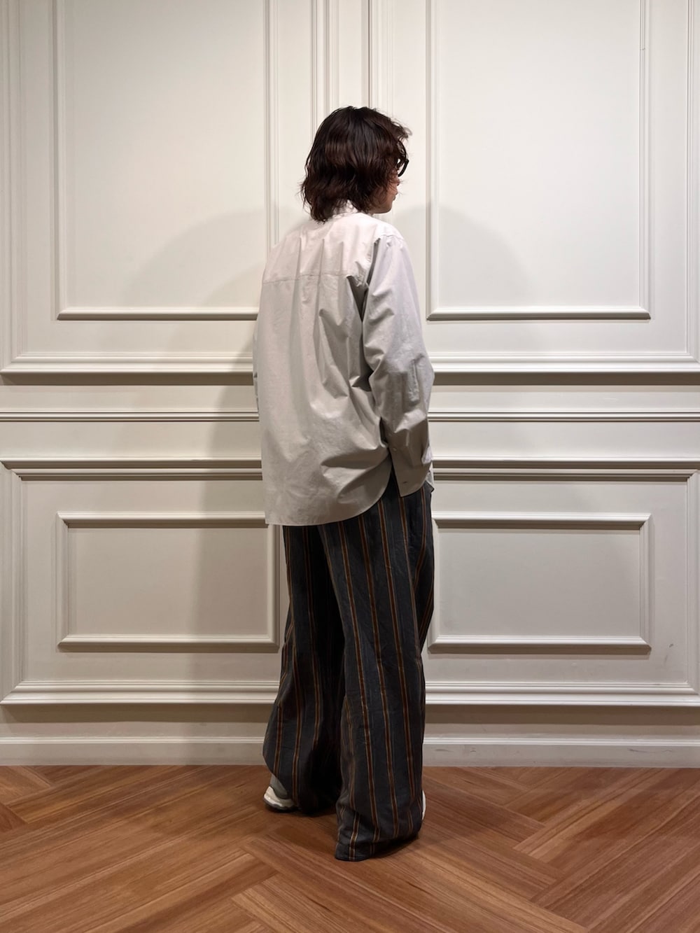 パープル系のニット/セーター、グレー系のシャツ/ブラウス、ホワイト系のスニーカーを着用したメンズの秋コーディネートの3枚目の写真