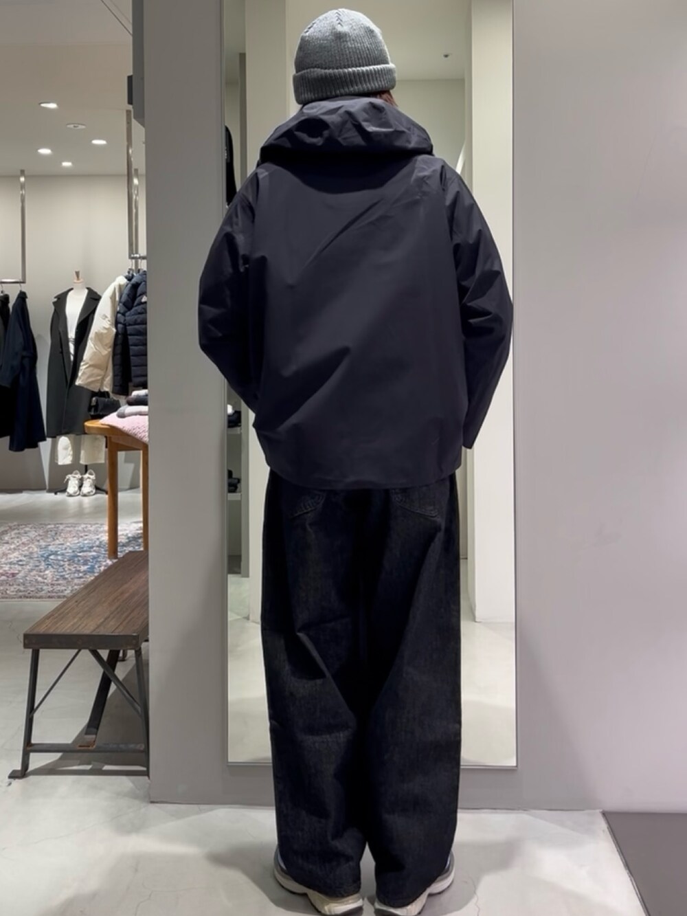 ブルー系のスニーカー、ベージュ系のニット/セーター、ブラック系のデニムパンツを着用したメンズの秋コーディネートの4枚目の写真