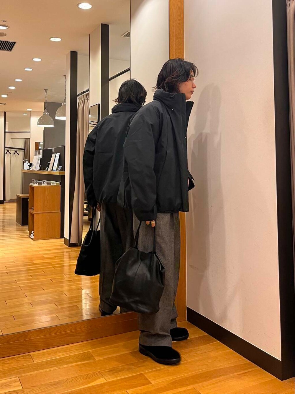 ブラック系のダウンジャケット/コート、ブラック系のニット/セーター、ブラック系のブーツを着用したメンズの秋コーディネートの4枚目の写真