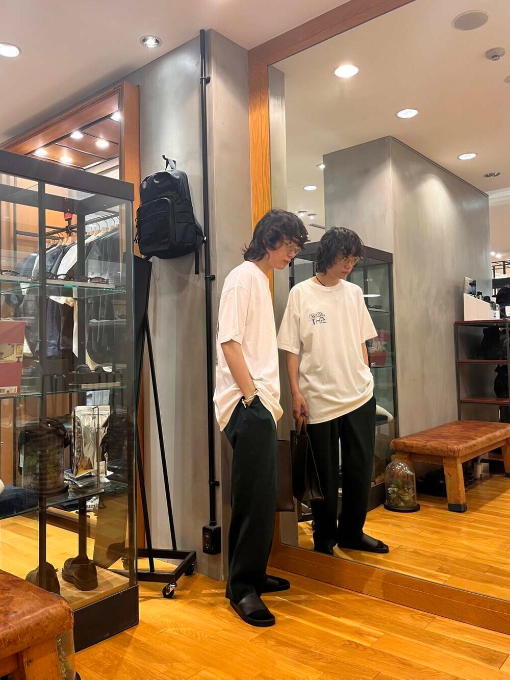 ブラック系のデニムパンツ、ブラック系のサンダル、ブラウン系のトートバッグを着用したメンズの夏コーディネートの2枚目の写真