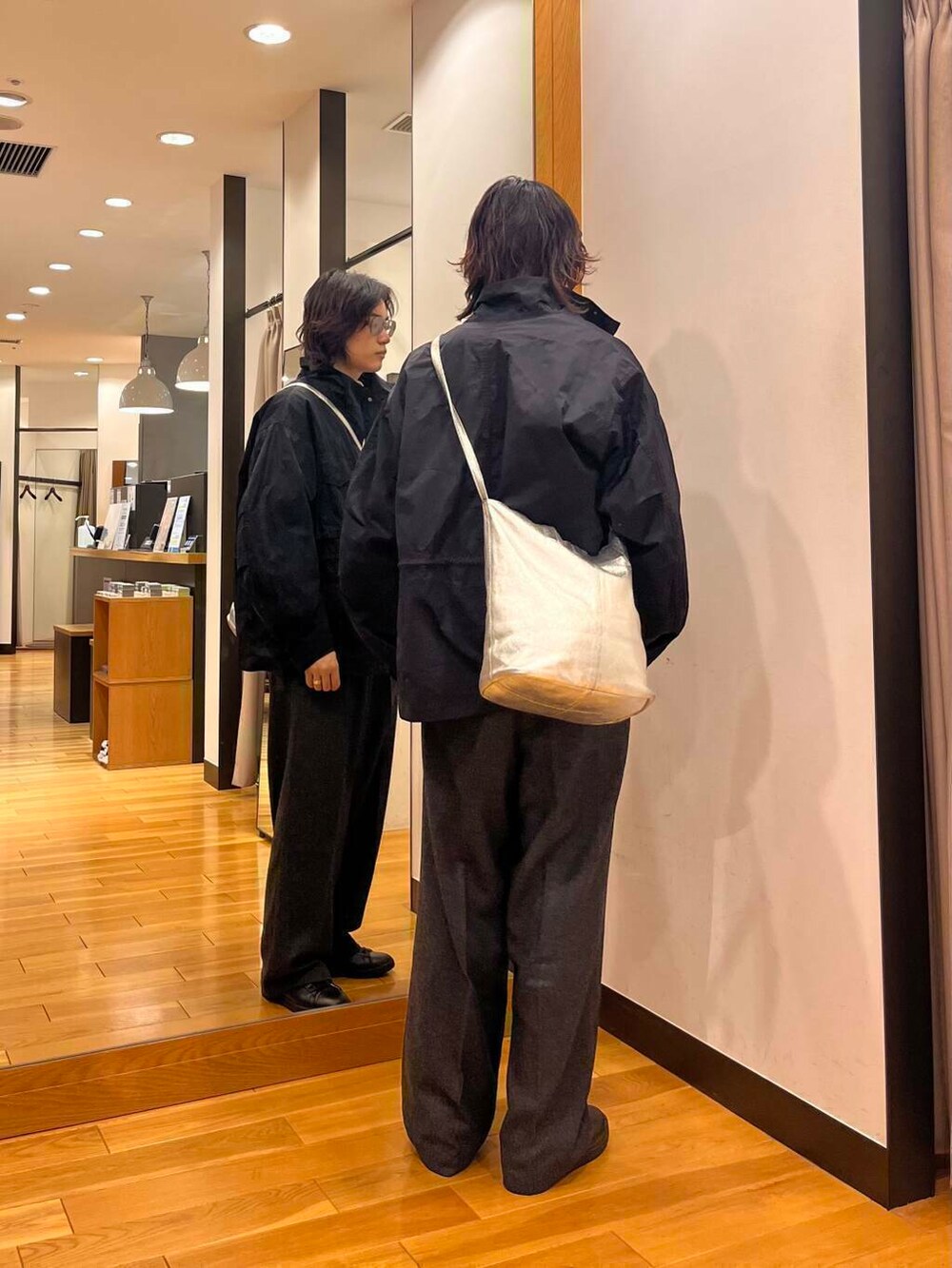 ブラック系のスニーカー、ブラック系のナイロンジャケット、ホワイト系のニット/セーターを着用したメンズの秋コーディネートの3枚目の写真