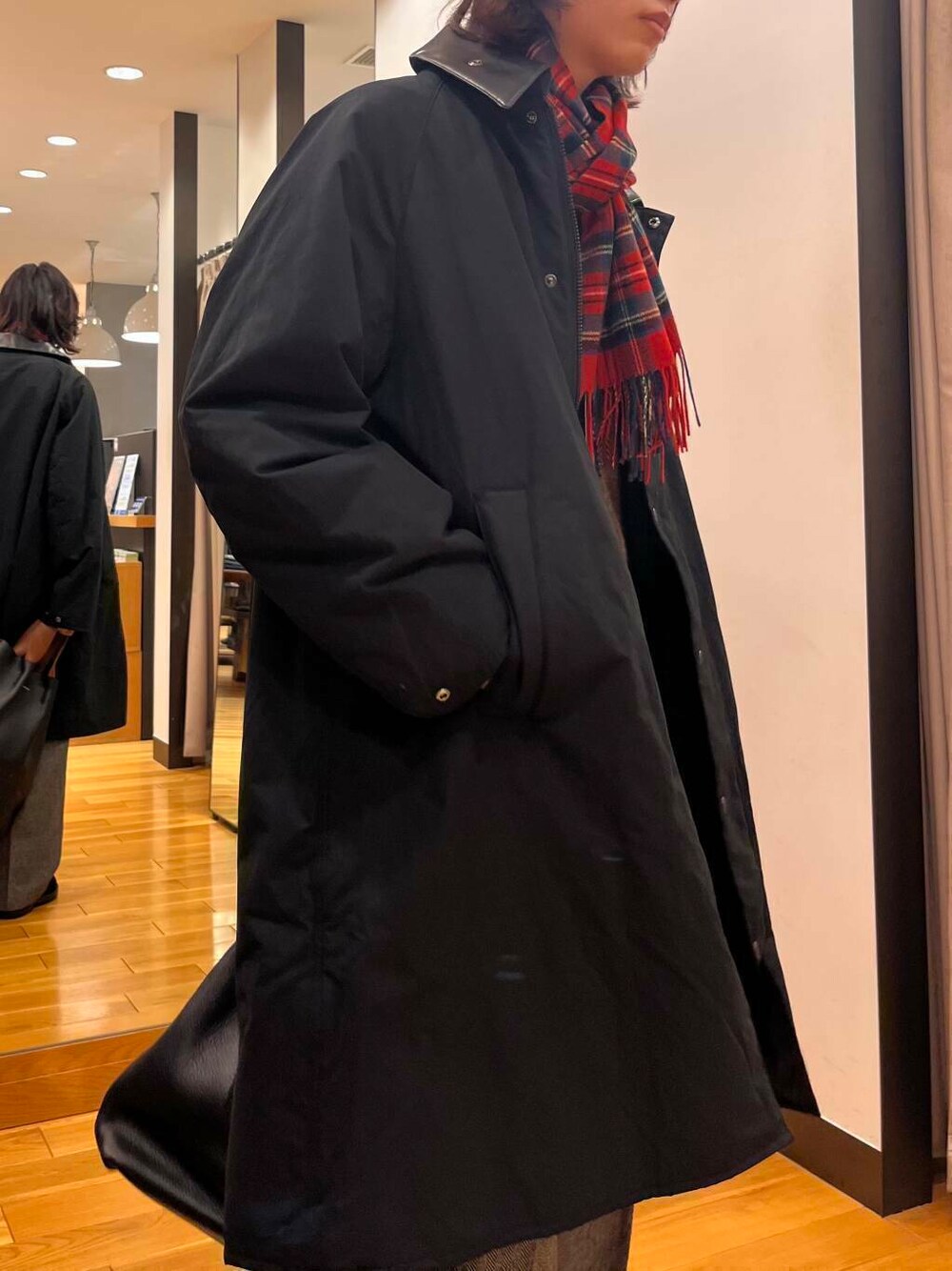 ブラック系のステンカラーコート、ブラック系のブーツ、グレー系のスラックスを着用したメンズの秋コーディネートの4枚目の写真