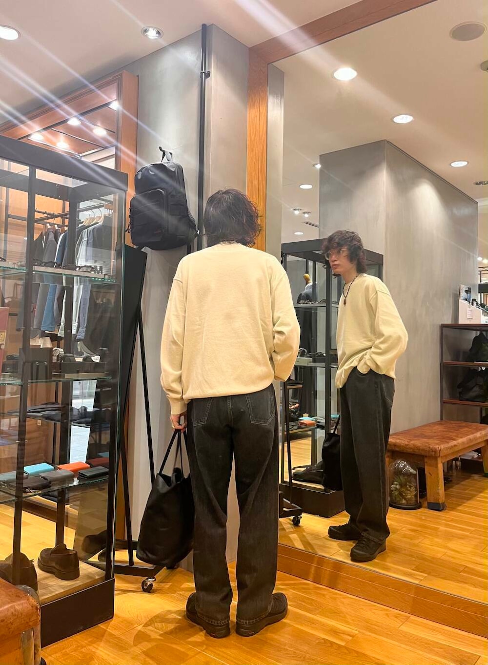 ブラック系のスニーカー、ブラック系のデニムパンツ、ホワイト系のニット/セーターを着用したメンズの夏コーディネートの3枚目の写真