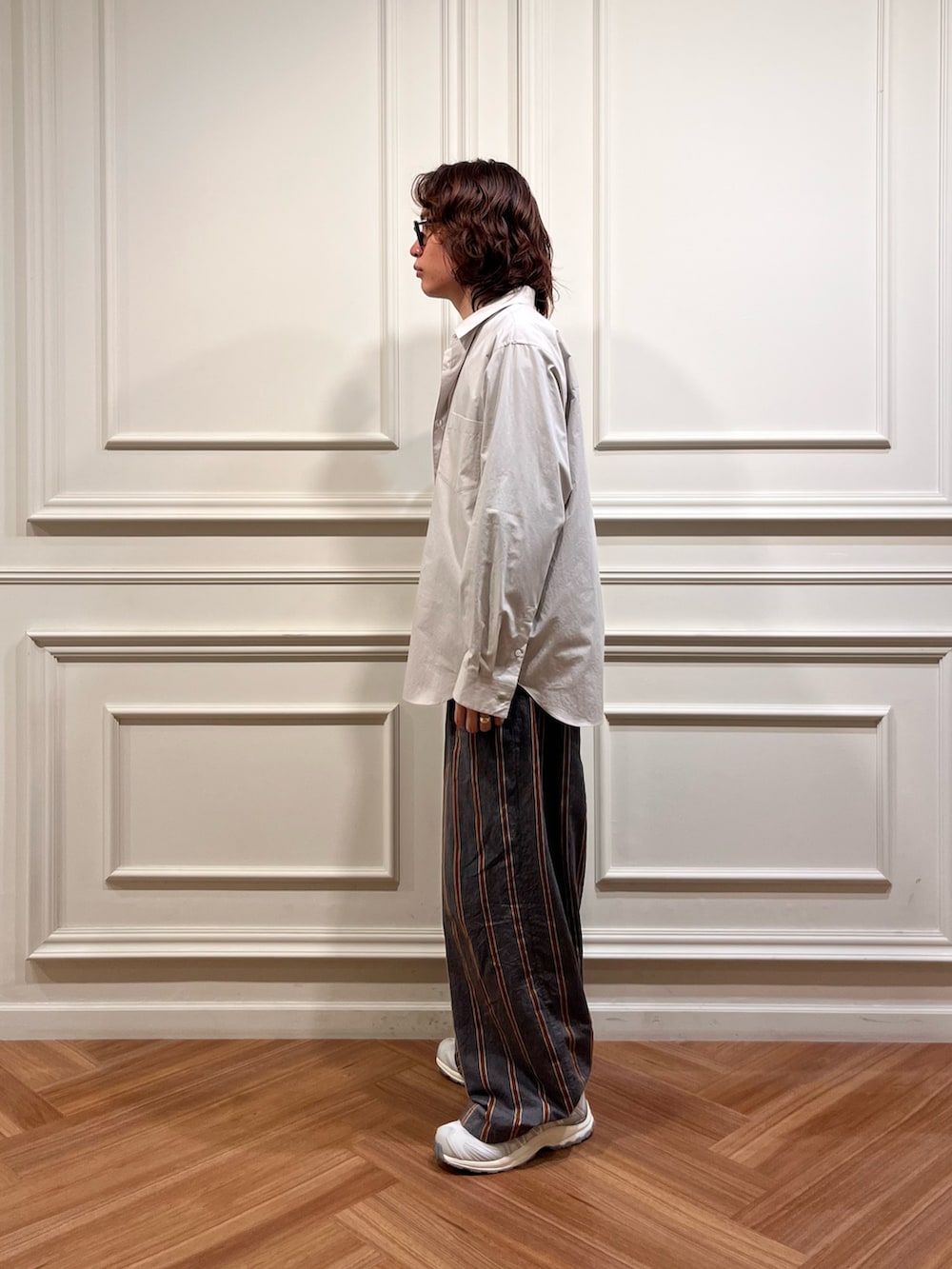 パープル系のニット/セーター、グレー系のシャツ/ブラウス、ホワイト系のスニーカーを着用したメンズの秋コーディネートの2枚目の写真