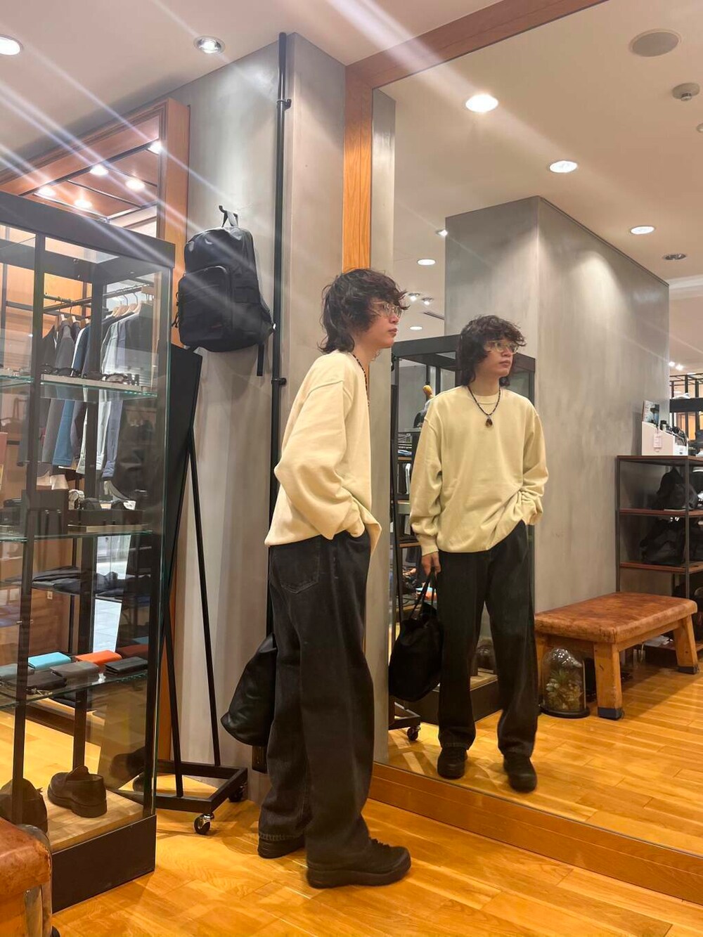 ブラック系のスニーカー、ブラック系のデニムパンツ、ホワイト系のニット/セーターを着用したメンズの夏コーディネートの2枚目の写真