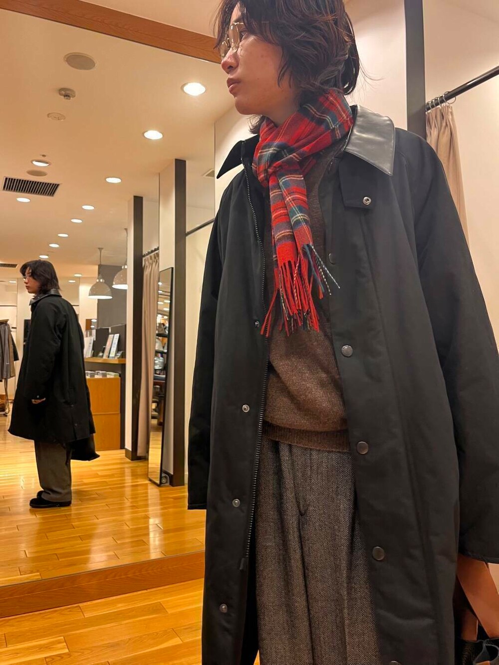 ブラック系のステンカラーコート、ブラック系のブーツ、グレー系のスラックスを着用したメンズの秋コーディネートの3枚目の写真