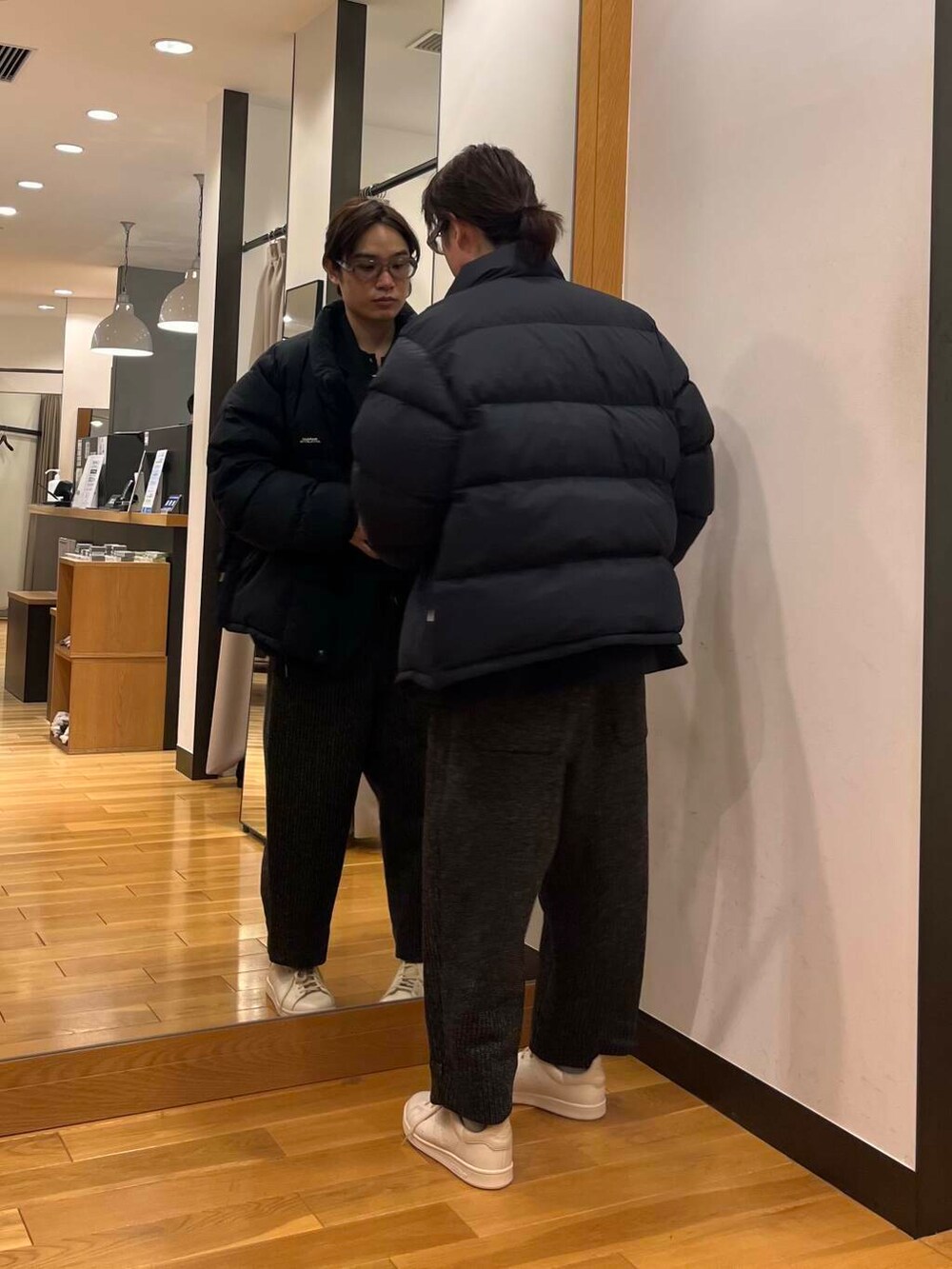 グレー系のその他パンツ、ブラック系のダウンジャケット/コート、グリーン系のニット/セーターを着用したメンズの冬コーディネートの2枚目の写真