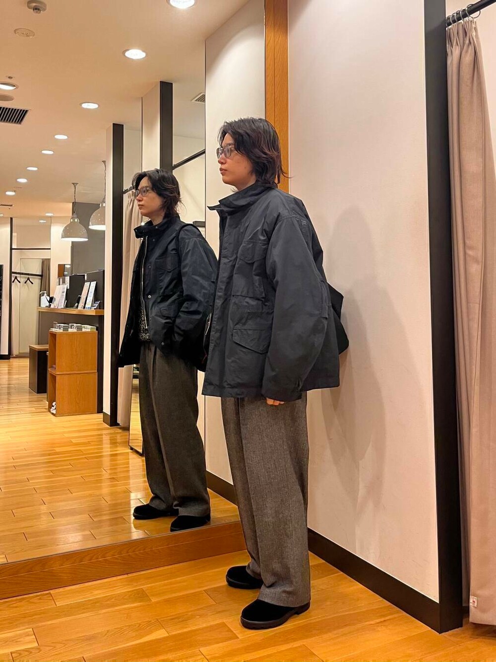 グレー系のナイロンジャケット、ブラック系のニット/セーター、ブラック系のブーツを着用したメンズの秋コーディネートの2枚目の写真