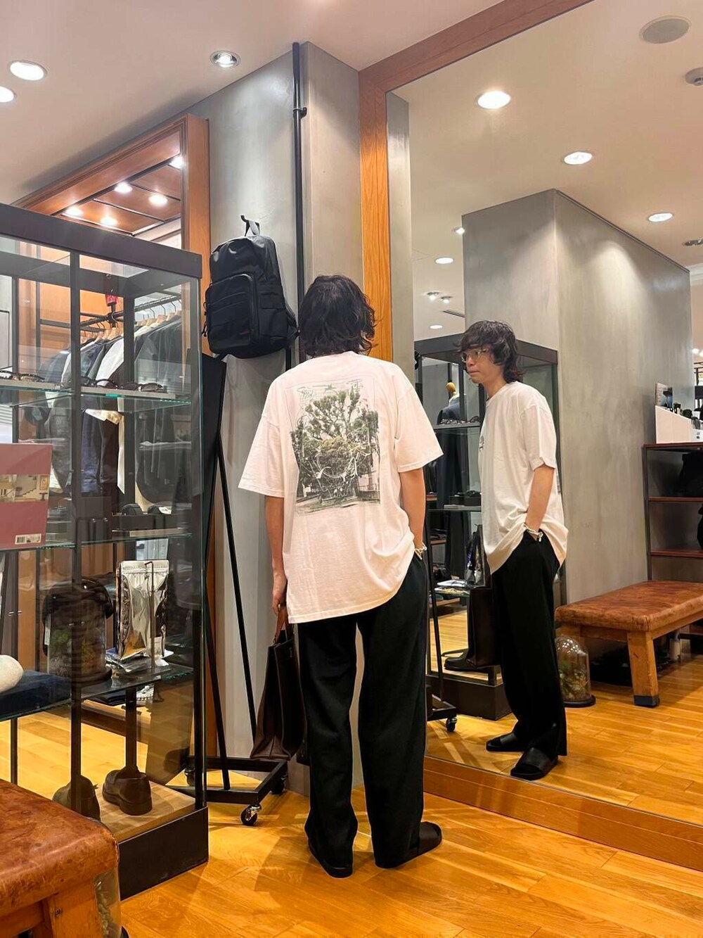 ブラック系のデニムパンツ、ブラック系のサンダル、ブラウン系のトートバッグを着用したメンズの夏コーディネートの3枚目の写真