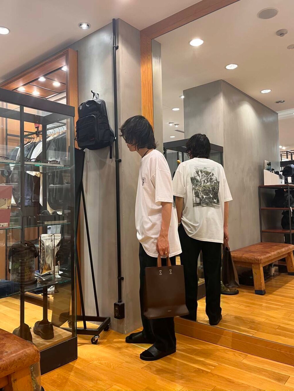 ブラック系のデニムパンツ、ブラック系のサンダル、ブラウン系のトートバッグを着用したメンズの夏コーディネートの4枚目の写真