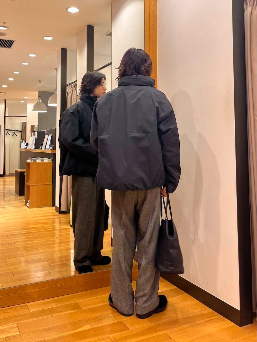 ブラック系のダウンジャケット/コート、ブラック系のニット/セーター、ブラック系のブーツを着用したメンズの秋コーディネートの3枚目の写真