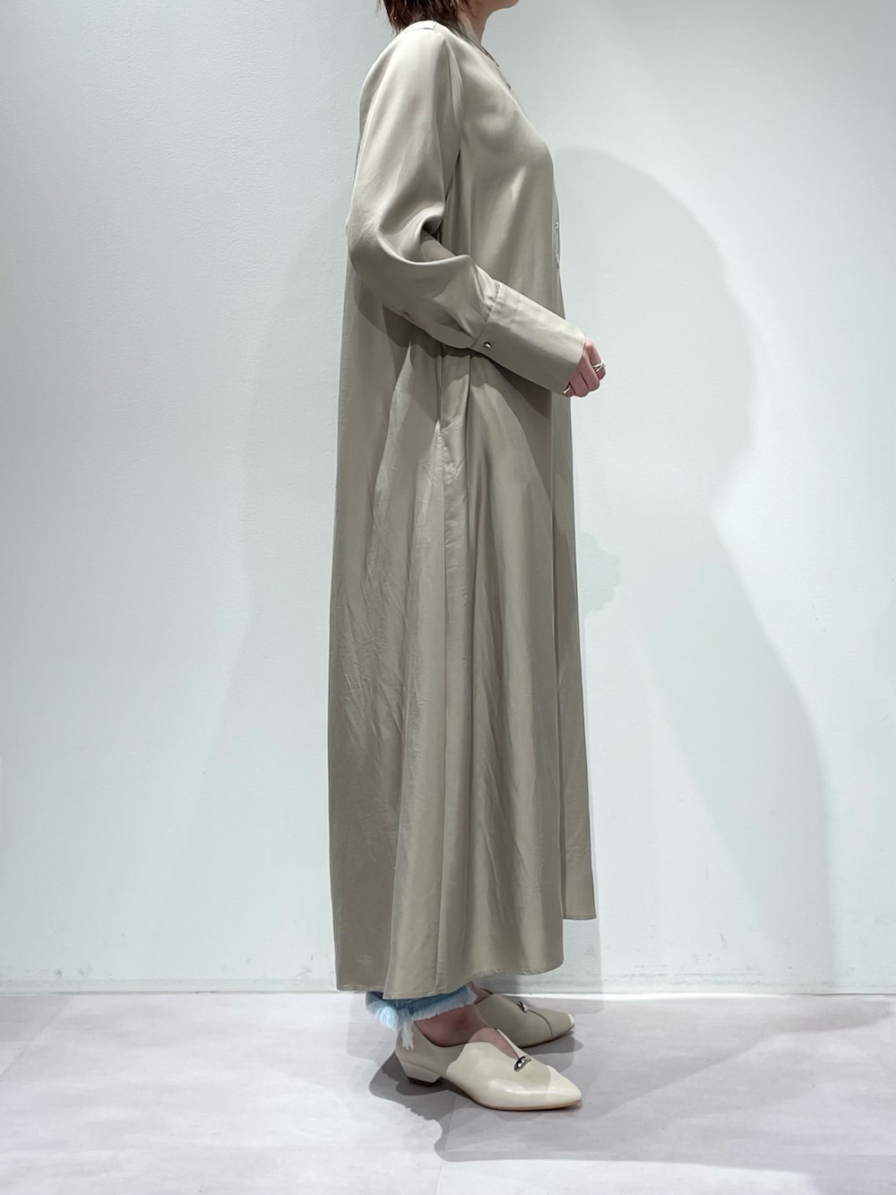 ベージュ系のワンピース、ブルー系のデニムパンツを着用したレディースの春コーディネートの2枚目の写真