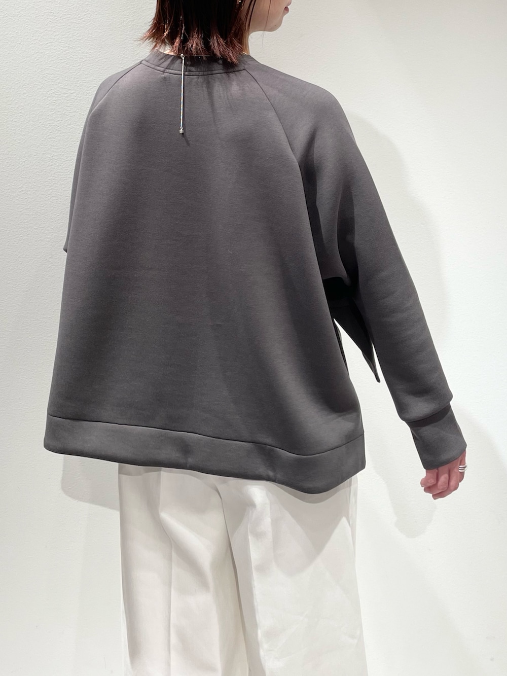 グレー系のスウェット、ホワイト系のデニムパンツ、シルバー系のネックレスを着用したレディースの冬コーディネートの6枚目の写真