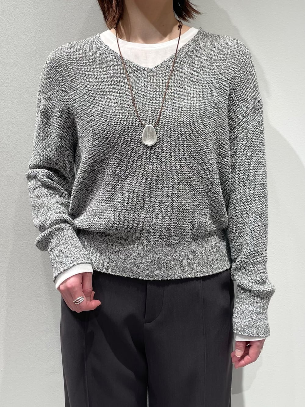 グレー系のその他パンツ、グレー系のニット/セーター、ホワイト系のTシャツ/カットソーを着用したレディースの春コーディネートの4枚目の写真