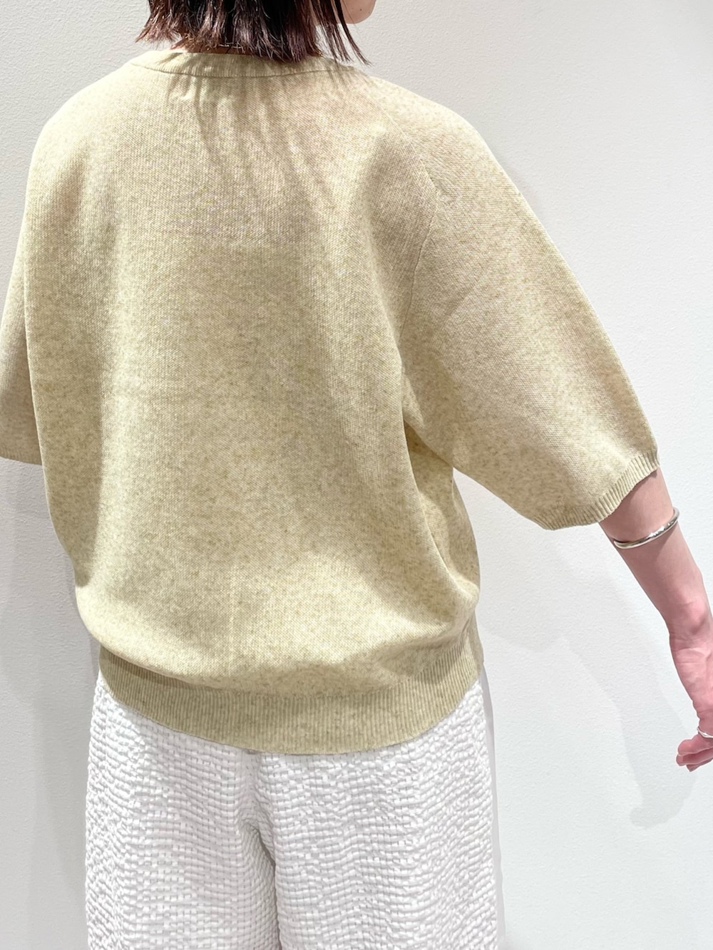 イエロー系のニット/セーター、ホワイト系のその他パンツ、ブラウン系のサンダルを着用したレディースの夏コーディネートの6枚目の写真