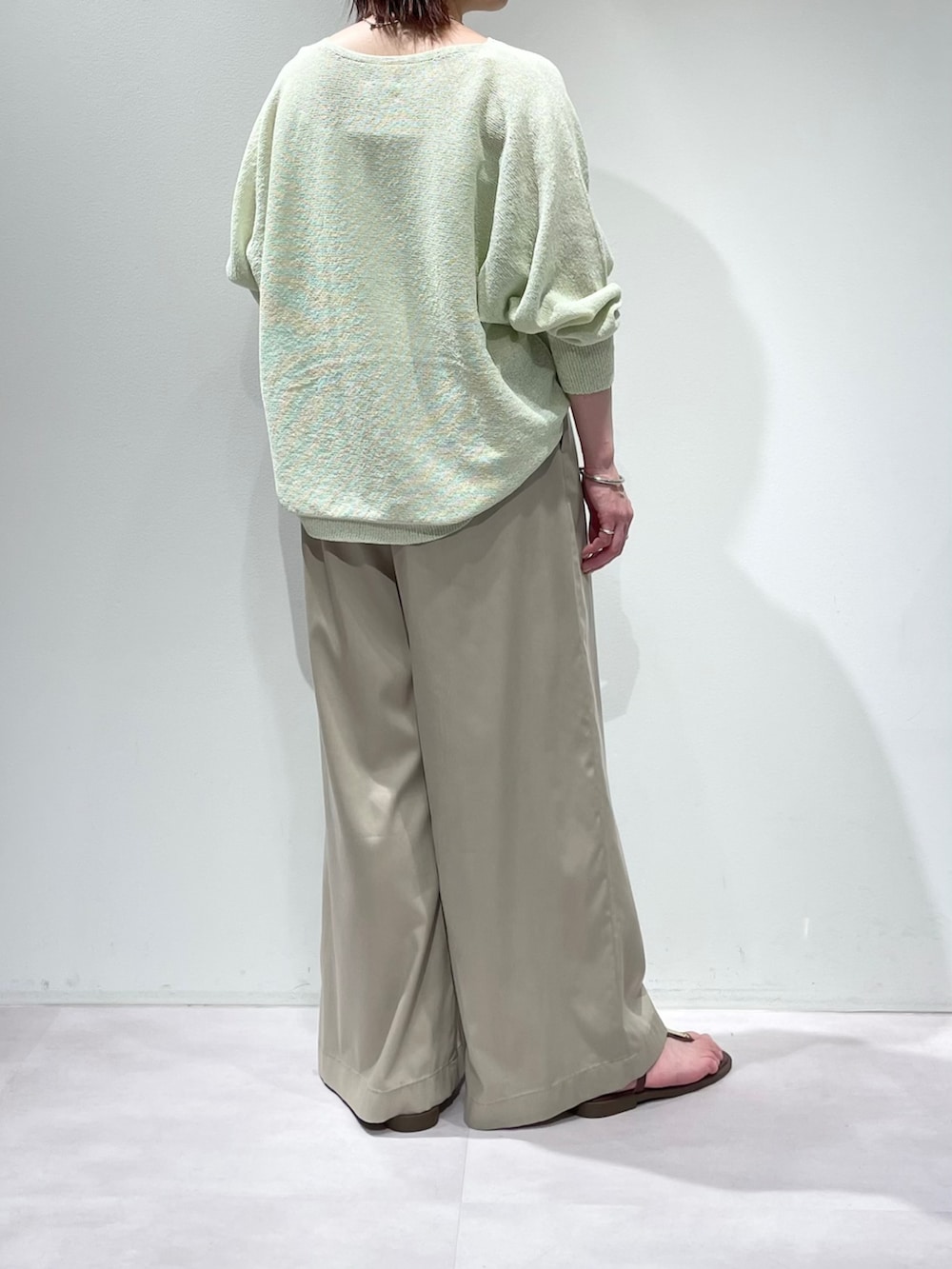 グリーン系のニット/セーター、ベージュ系のその他パンツ、シルバー系のネックレスを着用したレディースの春コーディネートの3枚目の写真