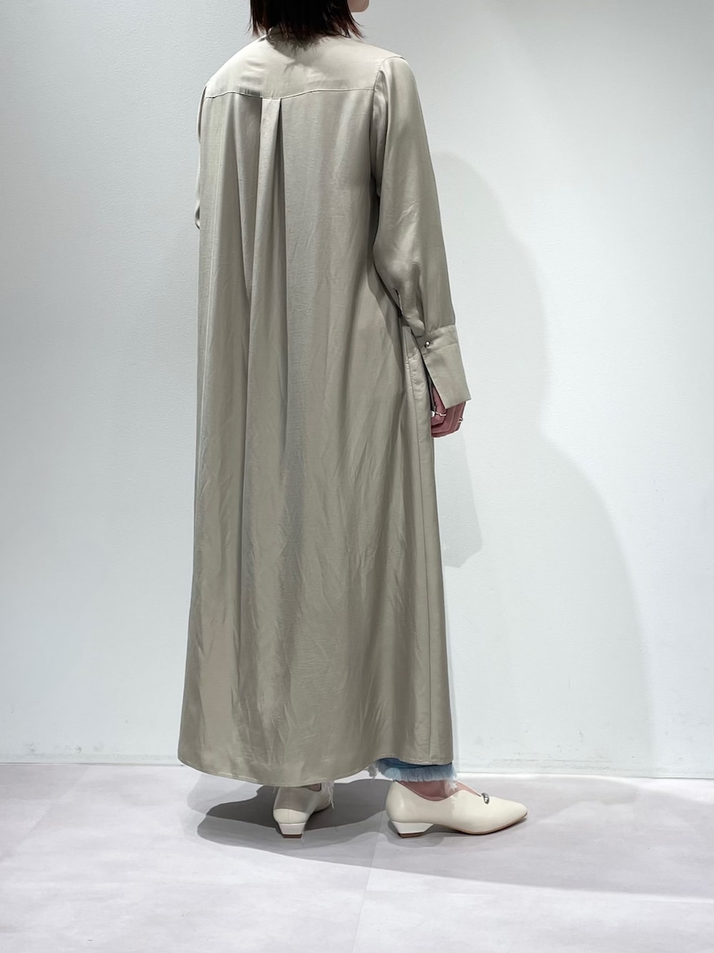 ベージュ系のワンピース、ブルー系のデニムパンツを着用したレディースの春コーディネートの3枚目の写真