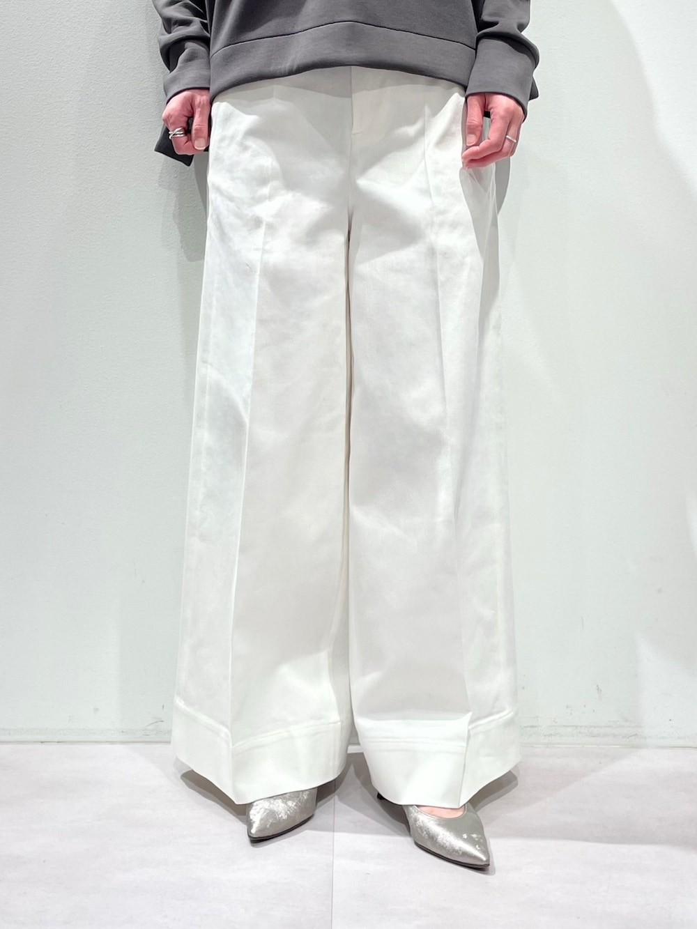 グレー系のスウェット、ホワイト系のデニムパンツ、シルバー系のネックレスを着用したレディースの冬コーディネートの7枚目の写真