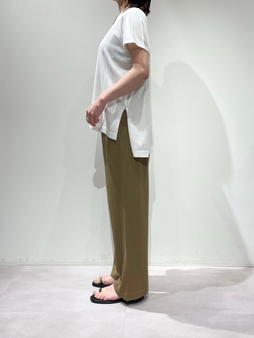 ベージュ系のその他パンツ、ホワイト系のニット/セーター、ブラック系のネックレスを着用したレディースの夏コーディネートの2枚目の写真
