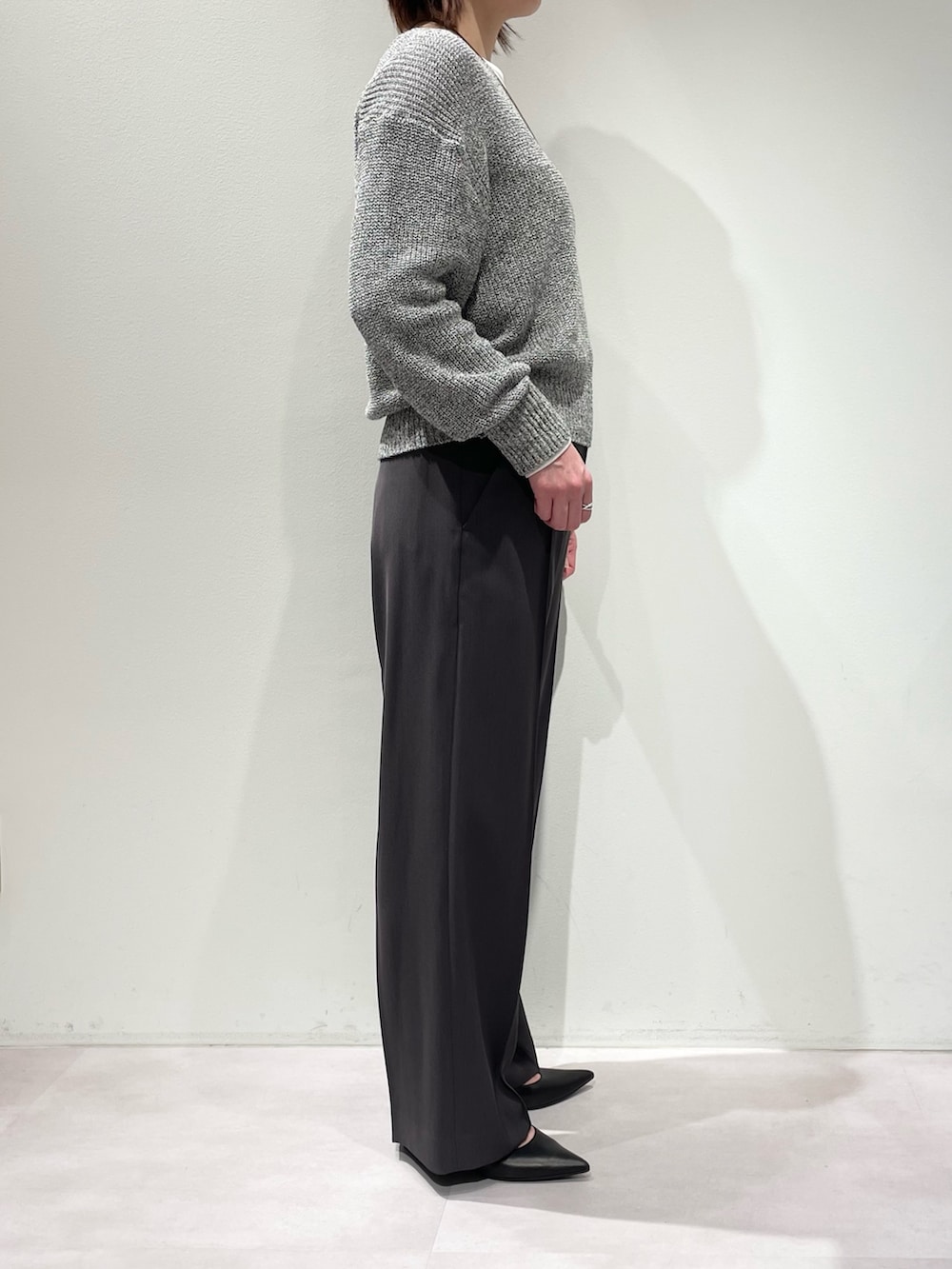 グレー系のその他パンツ、グレー系のニット/セーター、ホワイト系のTシャツ/カットソーを着用したレディースの春コーディネートの2枚目の写真