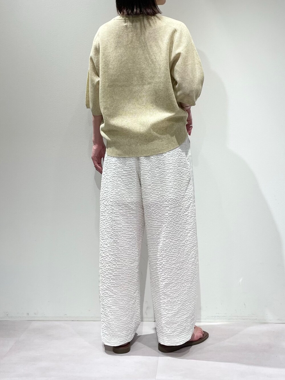 イエロー系のニット/セーター、ホワイト系のその他パンツ、ブラウン系のサンダルを着用したレディースの夏コーディネートの3枚目の写真