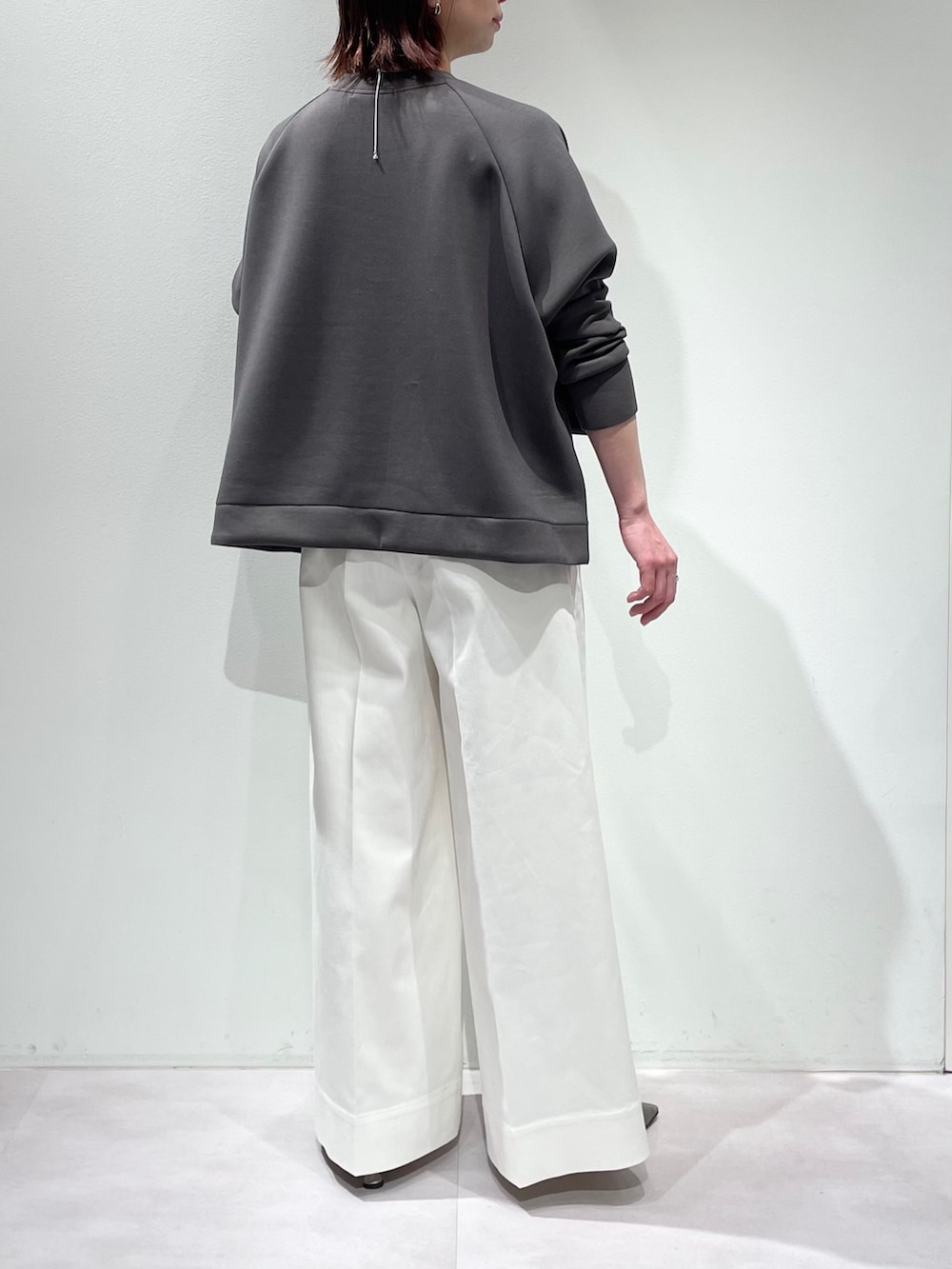 グレー系のスウェット、ホワイト系のデニムパンツ、シルバー系のネックレスを着用したレディースの冬コーディネートの3枚目の写真