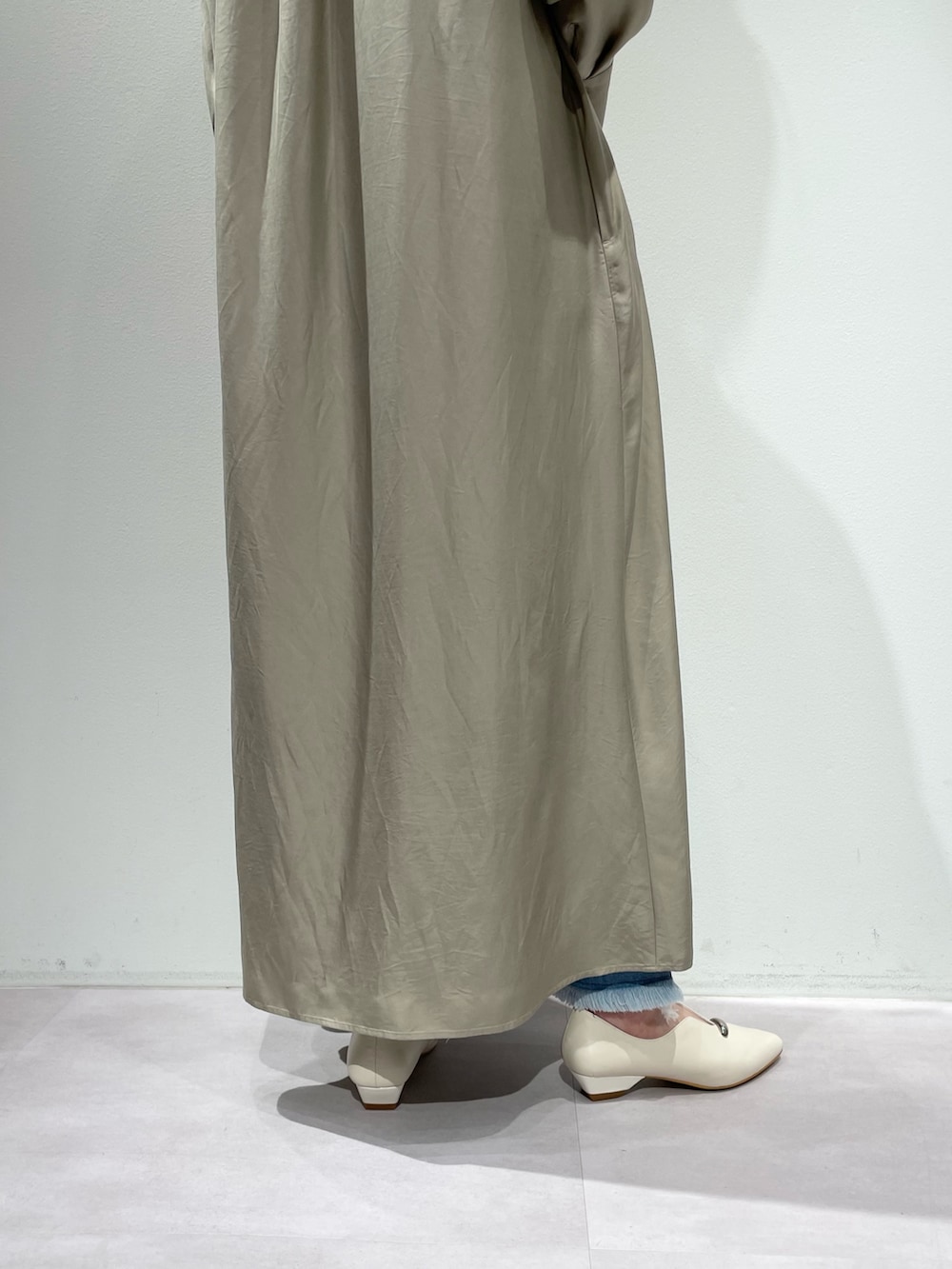 ベージュ系のワンピース、ブルー系のデニムパンツを着用したレディースの春コーディネートの9枚目の写真