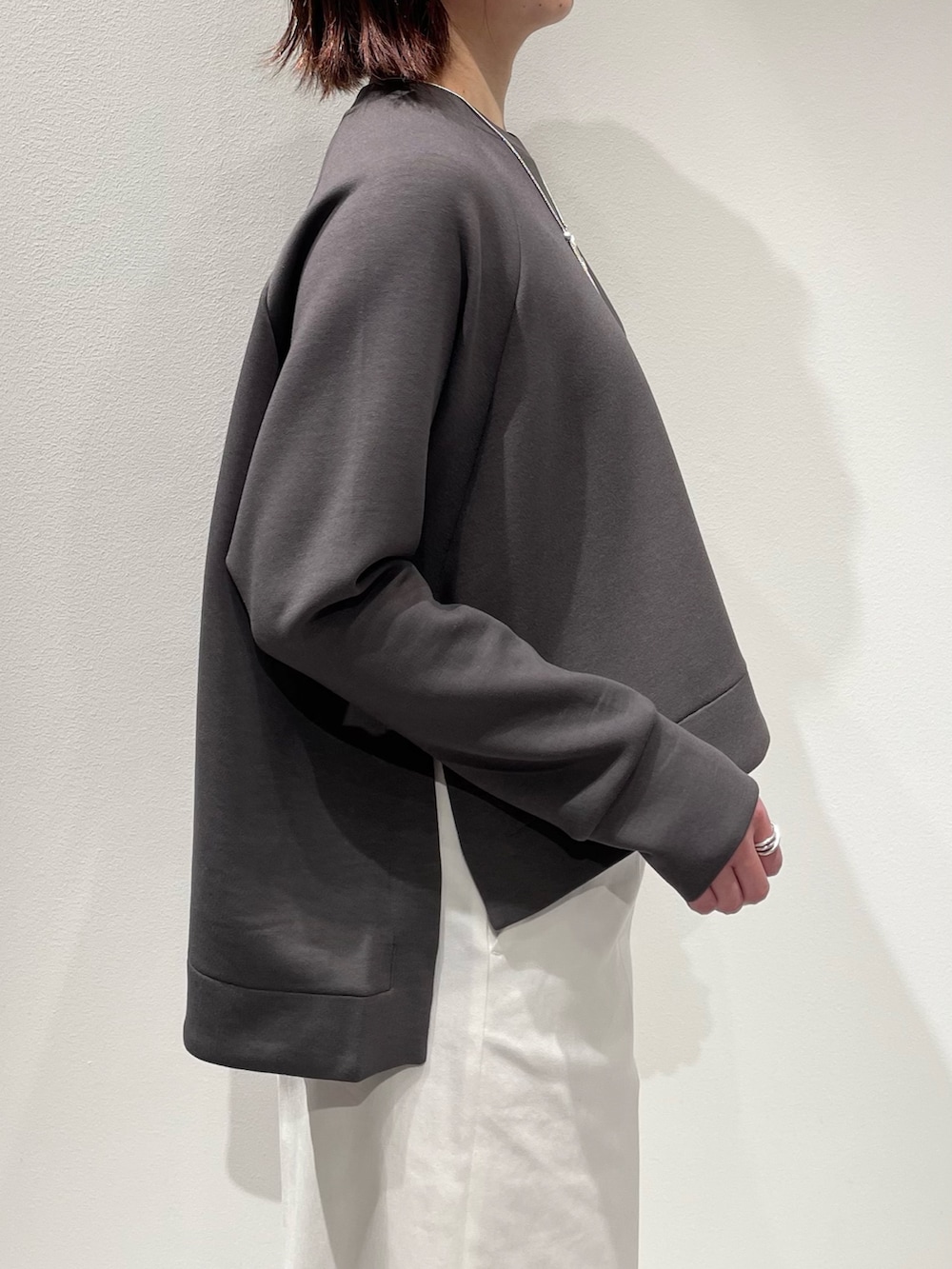 グレー系のスウェット、ホワイト系のデニムパンツ、シルバー系のネックレスを着用したレディースの冬コーディネートの5枚目の写真