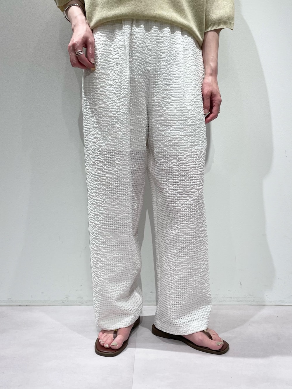イエロー系のニット/セーター、ホワイト系のその他パンツ、ブラウン系のサンダルを着用したレディースの夏コーディネートの7枚目の写真