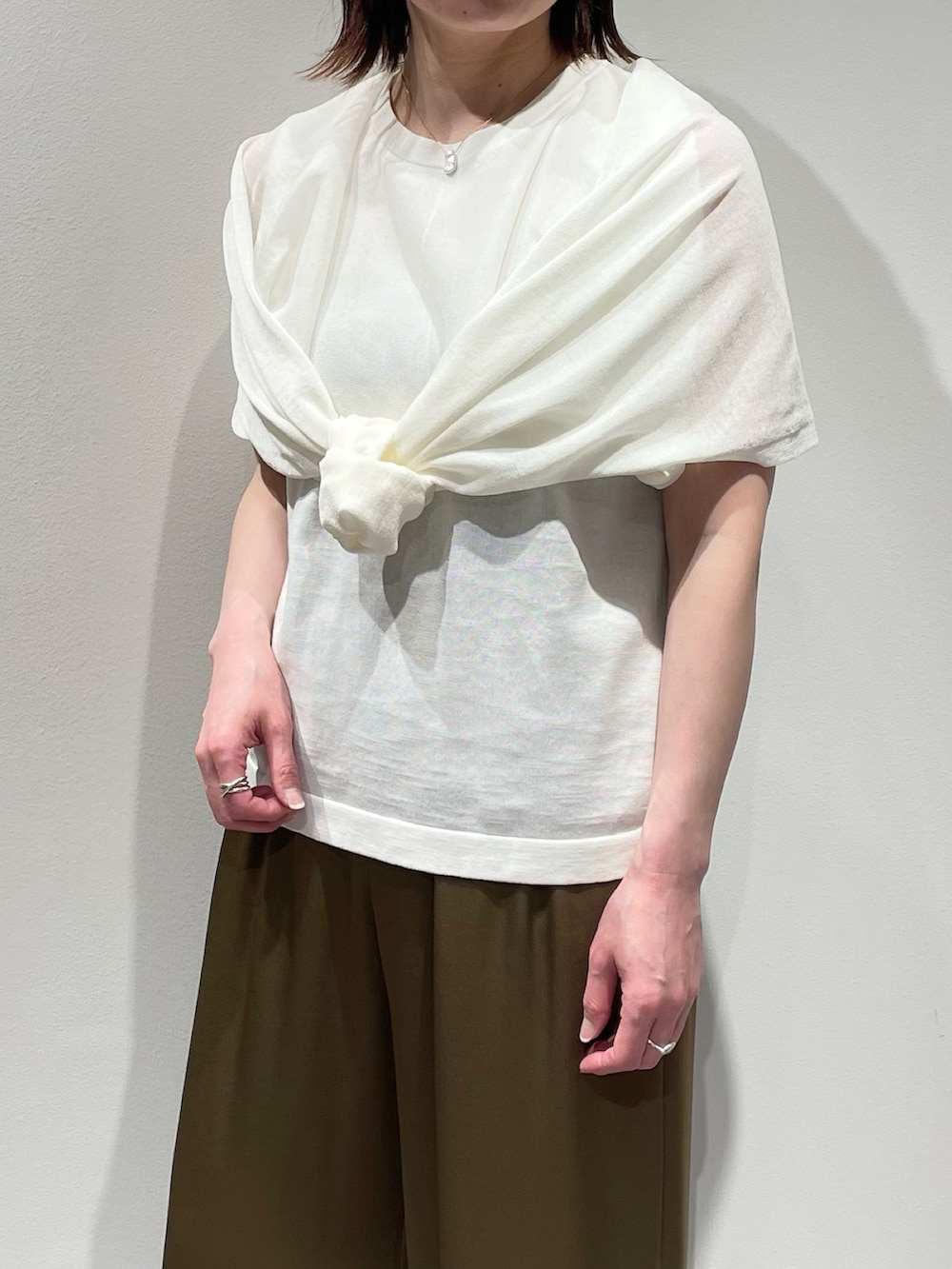 ホワイト系のニット/セーター、グリーン系のその他パンツ、ゴールド系のネックレスを着用したレディースの春コーディネートの7枚目の写真