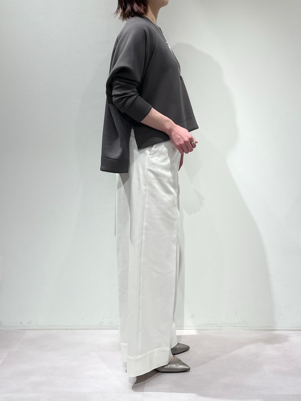 グレー系のスウェット、ホワイト系のデニムパンツ、シルバー系のネックレスを着用したレディースの冬コーディネートの2枚目の写真