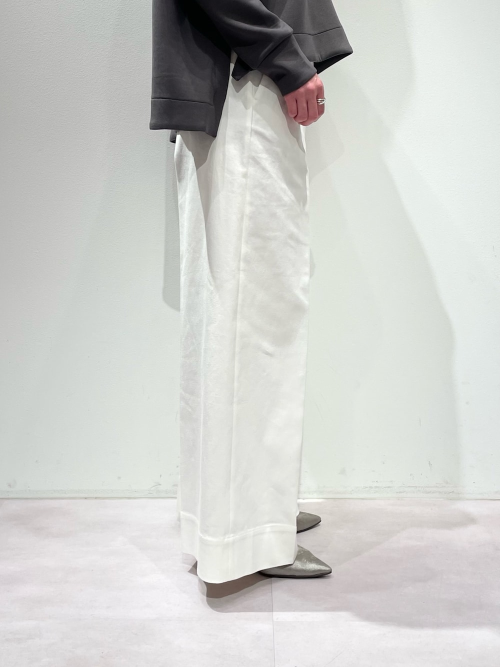 グレー系のスウェット、ホワイト系のデニムパンツ、シルバー系のネックレスを着用したレディースの冬コーディネートの8枚目の写真