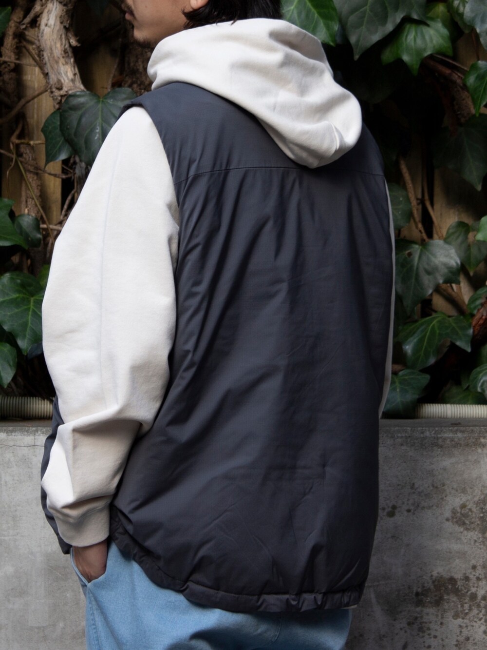 グレー系のベスト、ベージュ系のパーカー、ブルー系のその他パンツを着用したメンズの春コーディネートの4枚目の写真