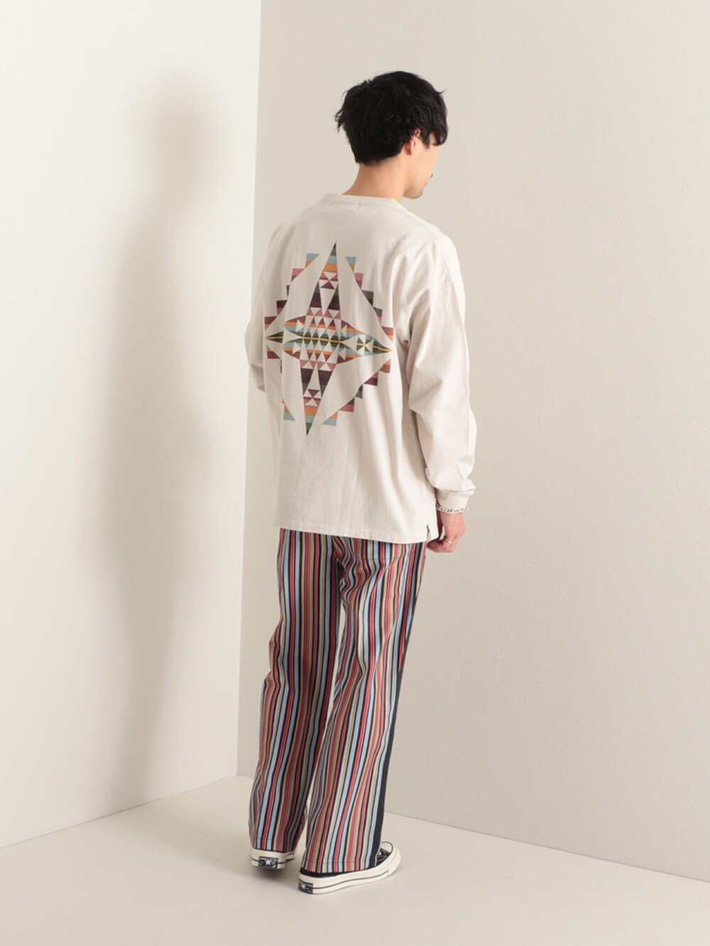 グリーン系のTシャツ/カットソー、ベージュ系のその他パンツ、ブラック系のスニーカーを着用したメンズの冬コーディネートの2枚目の写真