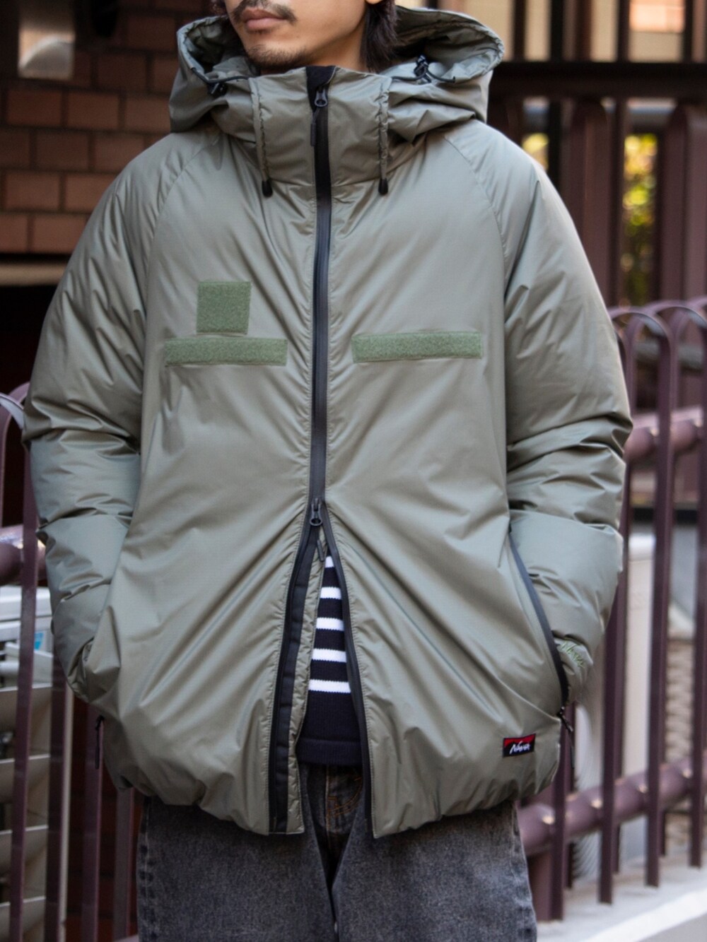 グリーン系のダウンジャケット/コート、ブルー系のニット/セーター、ブラック系のブーツを着用したメンズの冬コーディネートの2枚目の写真