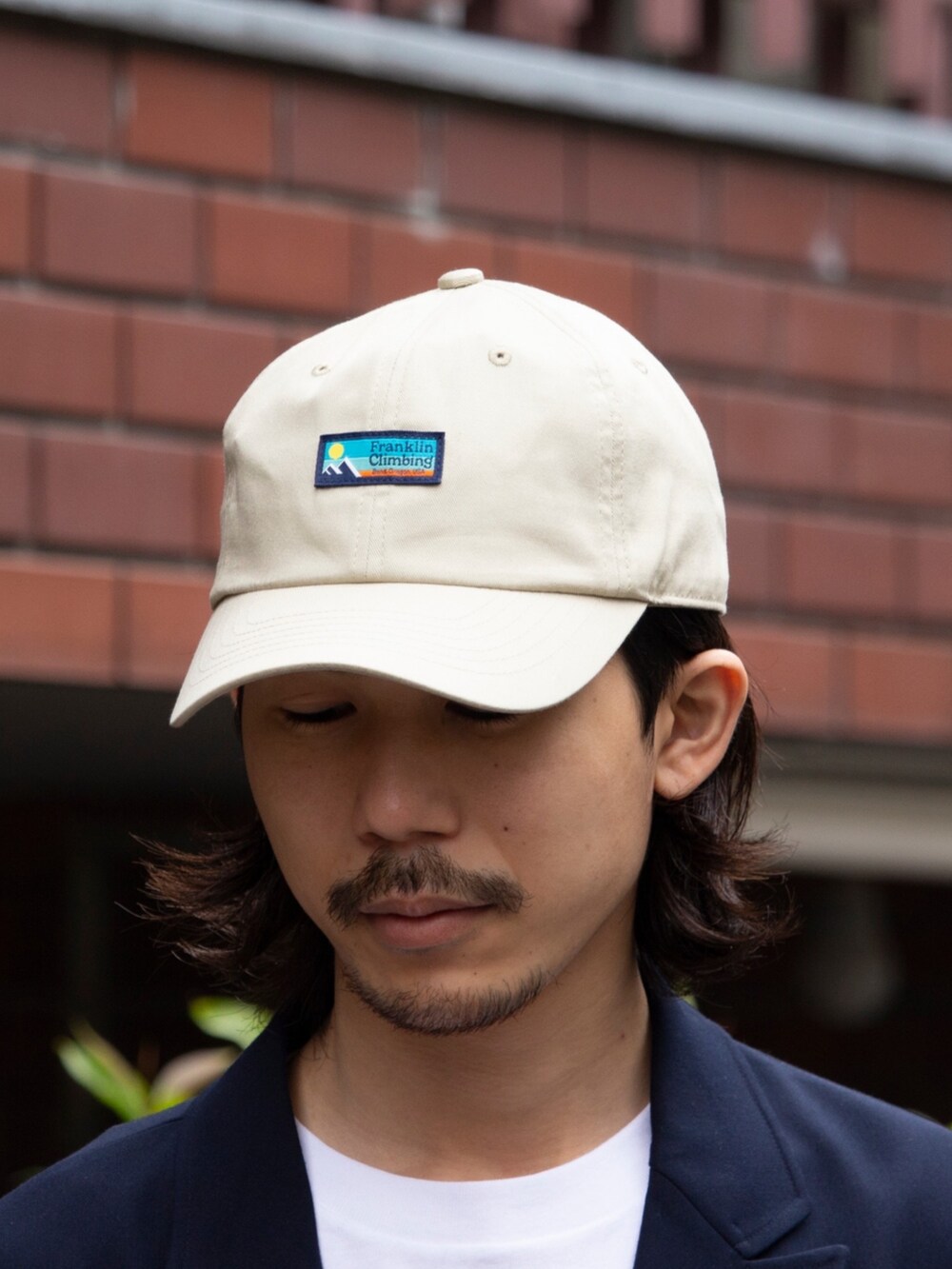 ホワイト系のデニムパンツ、ブラック系のサンダル、ブルー系のテーラードジャケットを着用したメンズの春コーディネートの5枚目の写真