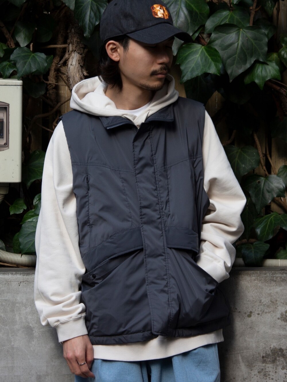 グレー系のベスト、ベージュ系のパーカー、ブルー系のその他パンツを着用したメンズの春コーディネートの5枚目の写真