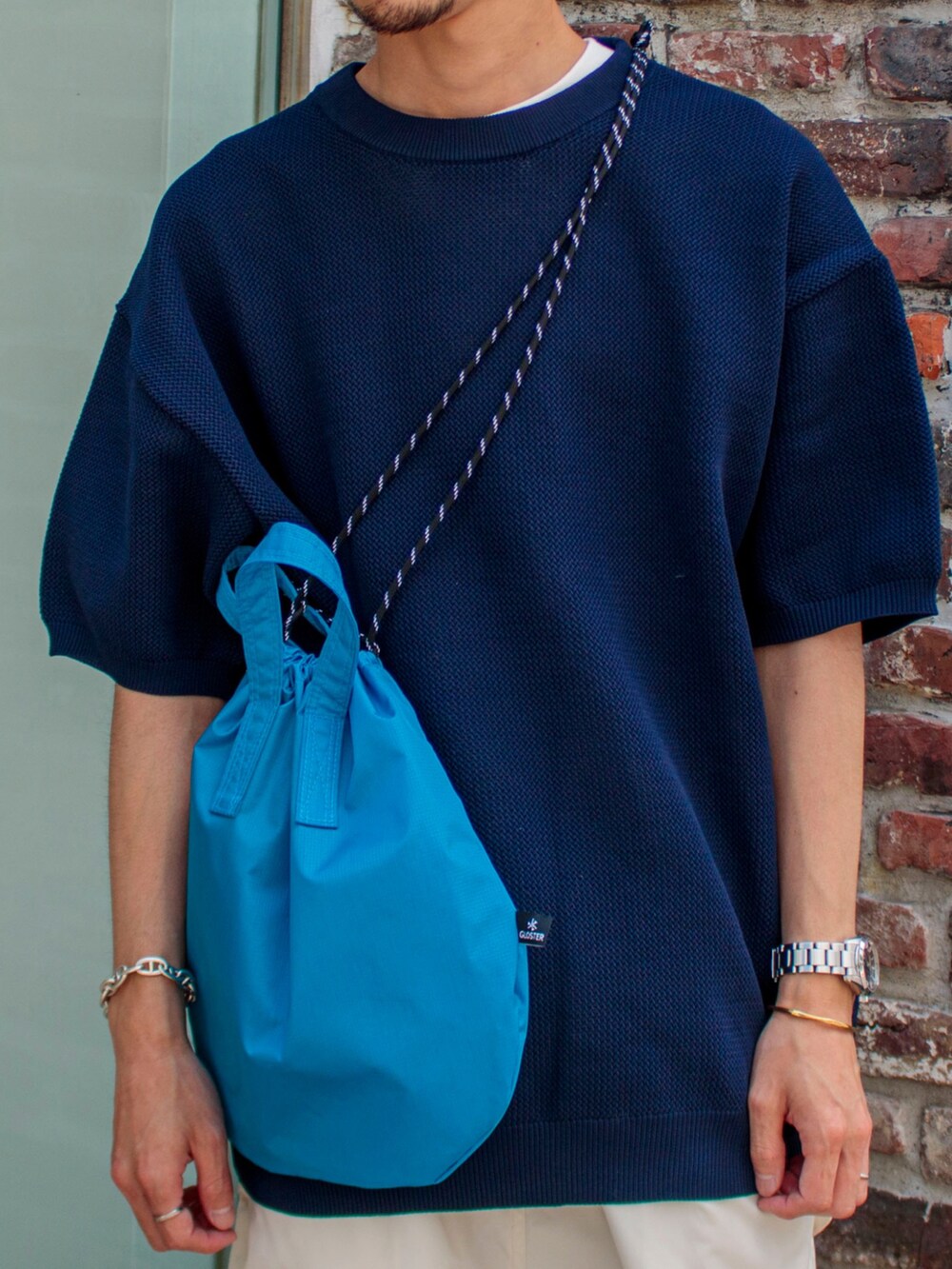 ブルー系のニット/セーター、ホワイト系のその他パンツ、ブラック系のサンダルを着用したメンズの夏コーディネートの2枚目の写真