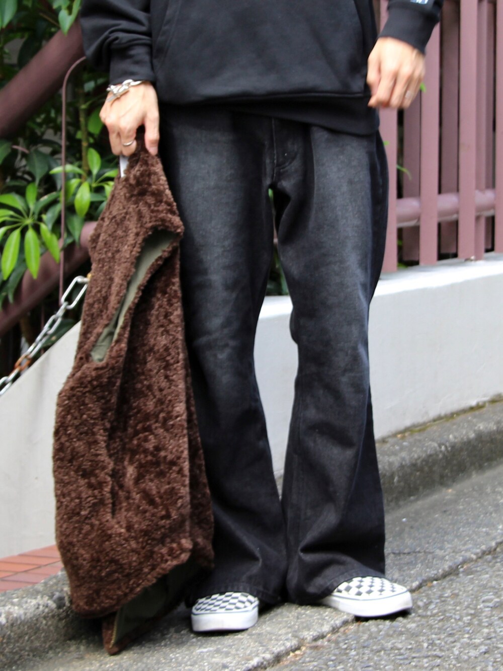 ブラウン系のベスト、ブラック系のパーカー、ブラック系のデニムパンツを着用したメンズの秋コーディネートの4枚目の写真