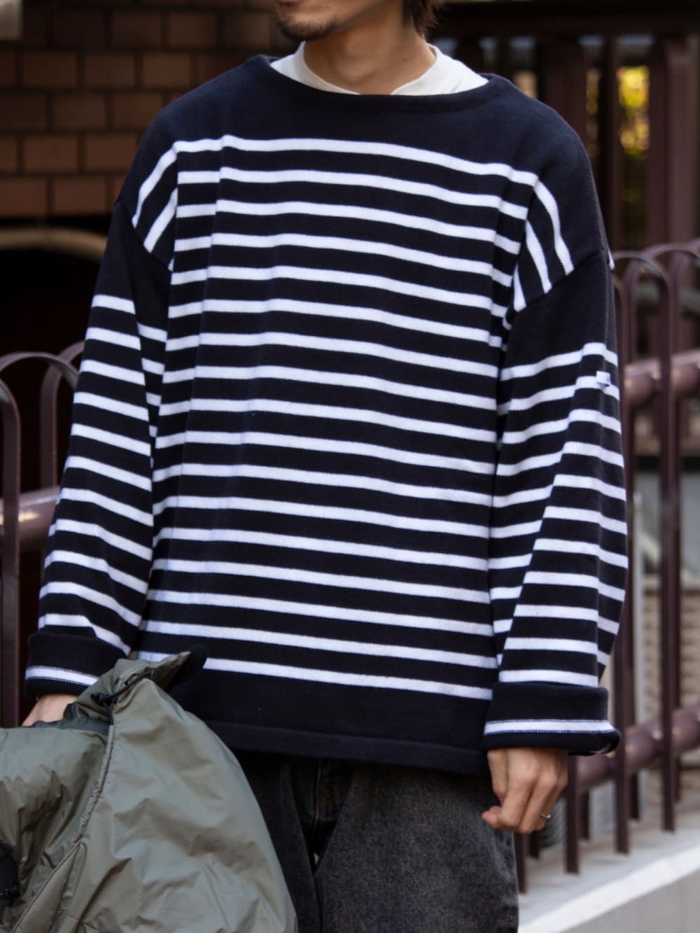 グリーン系のダウンジャケット/コート、ブルー系のニット/セーター、ブラック系のブーツを着用したメンズの冬コーディネートの3枚目の写真