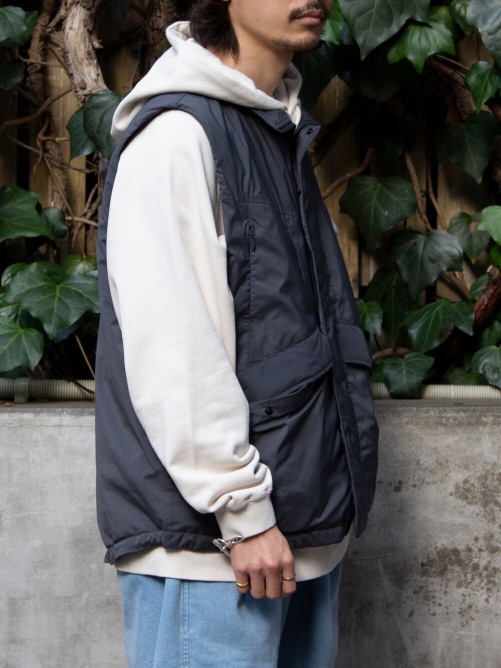 グレー系のベスト、ベージュ系のパーカー、ブルー系のその他パンツを着用したメンズの春コーディネートの3枚目の写真